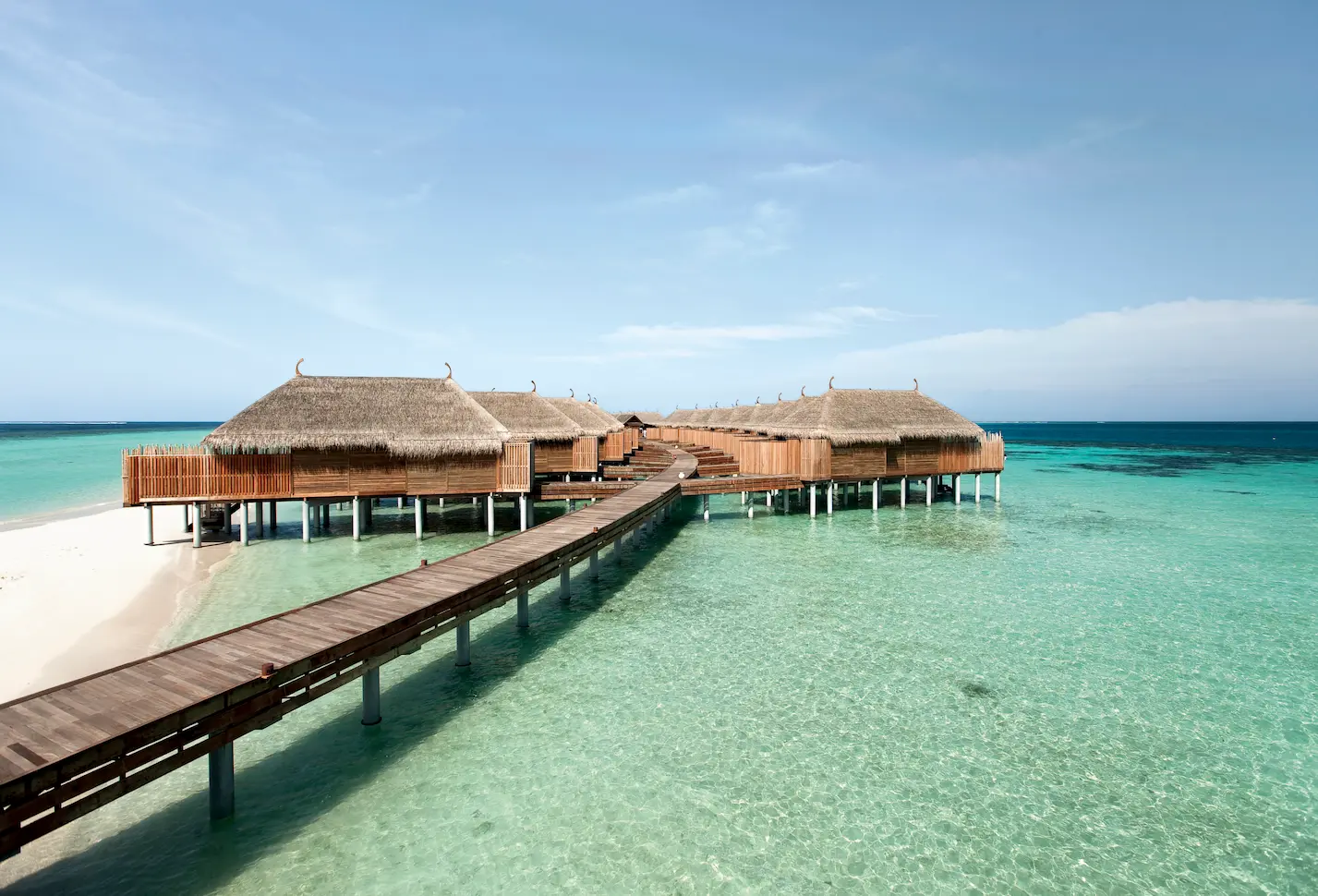 exterior view of the senior water villa at constance moofushi maldives with bright lagoon scenery