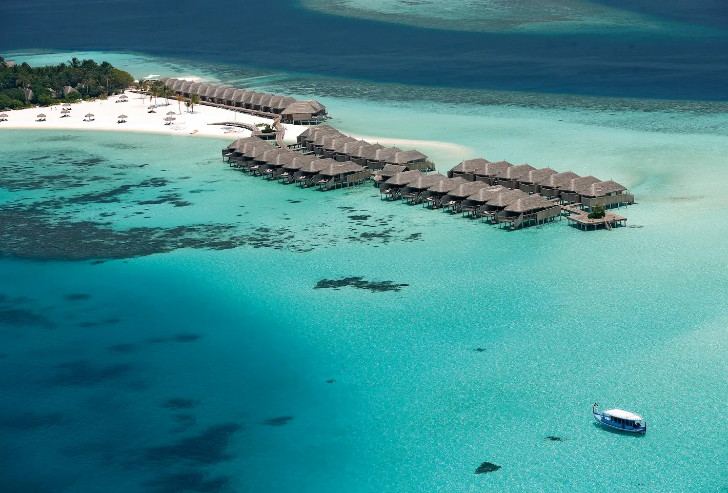 aerial view of the villas at constance moofushi maldives set above a bright turquoise lagoon