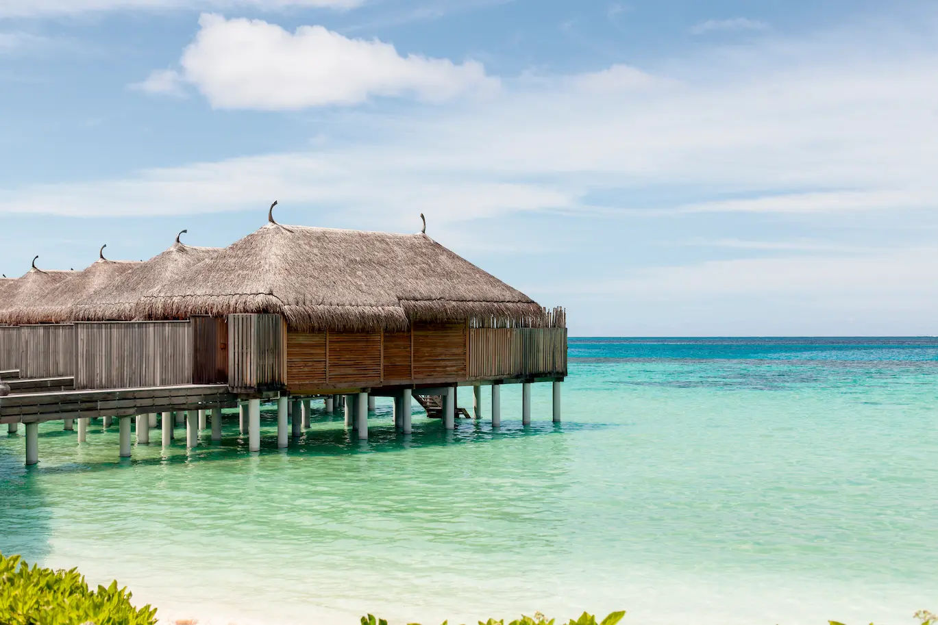 constance moofushi maldives water villa exterior in a calm lagoon setting