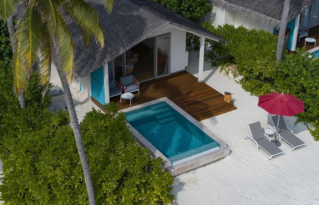striking exterior facade of the beach pool villa at cora cora maldives surrounded by tropical greenery and soft coastal light