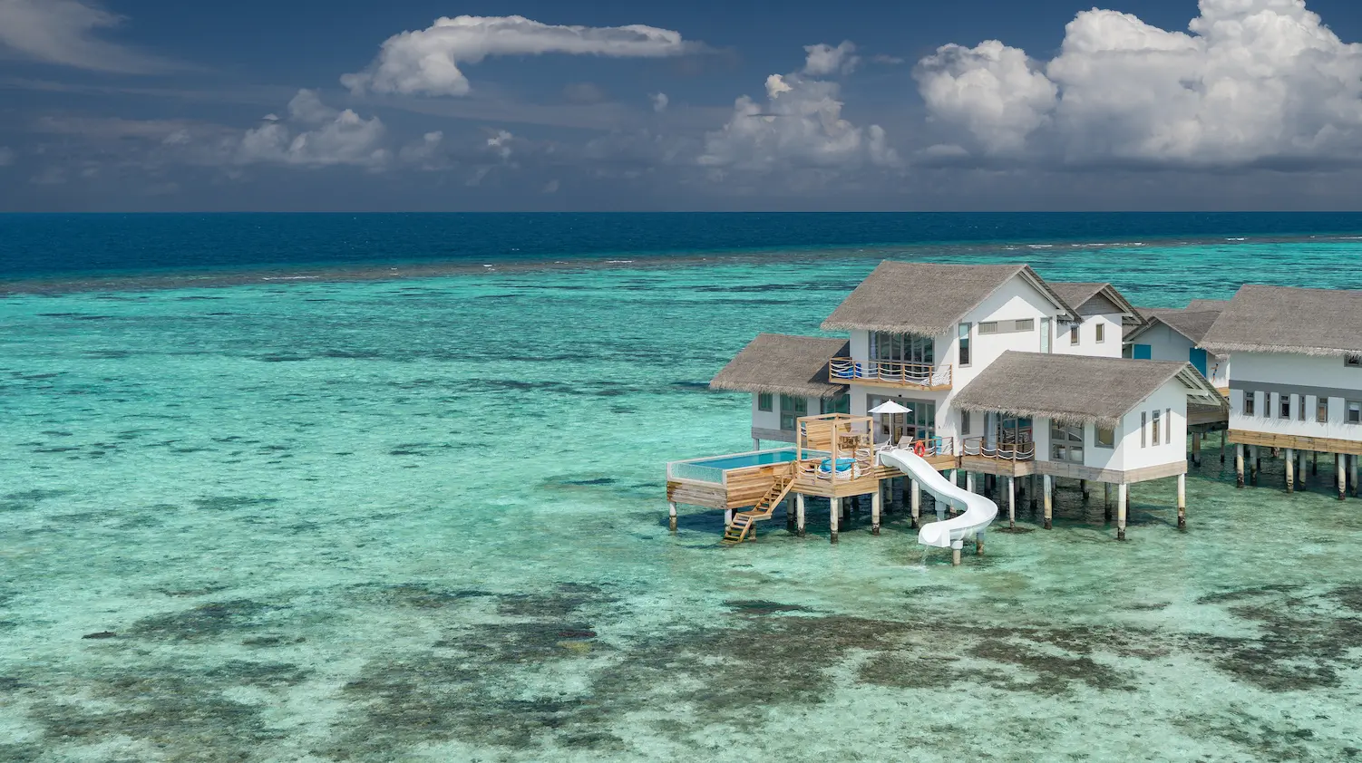 cora cora maldives two bedroom lagoon pool villa with slide captured in a scenic drone view above the turquoise lagoon and overwater luxury setting