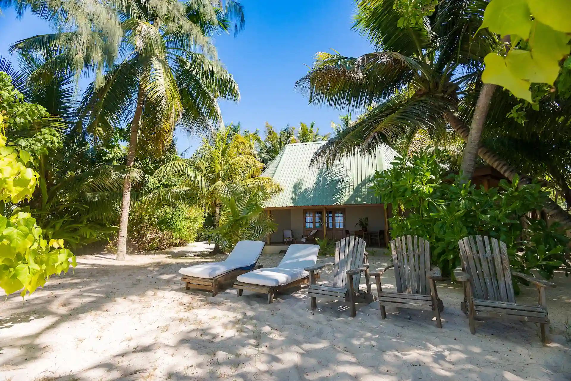 denis private island seychelles beach cottage loungers on private terrace with tropical garden views and steps leading to the white sand beach