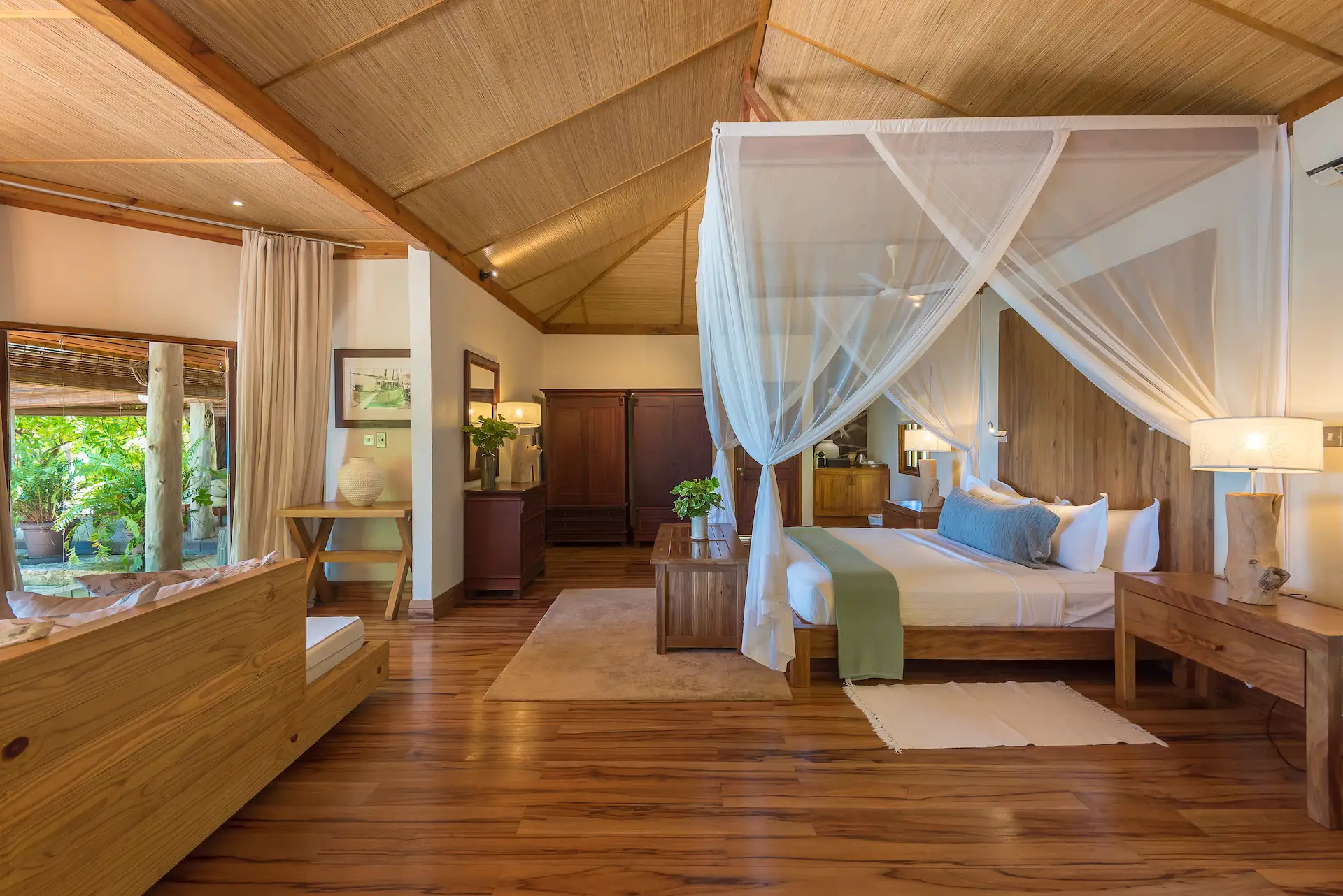 denis private island seychelles beach villa bedroom with king size bed, elegant island décor, and private terrace overlooking the turquoise ocean and tropical gardens