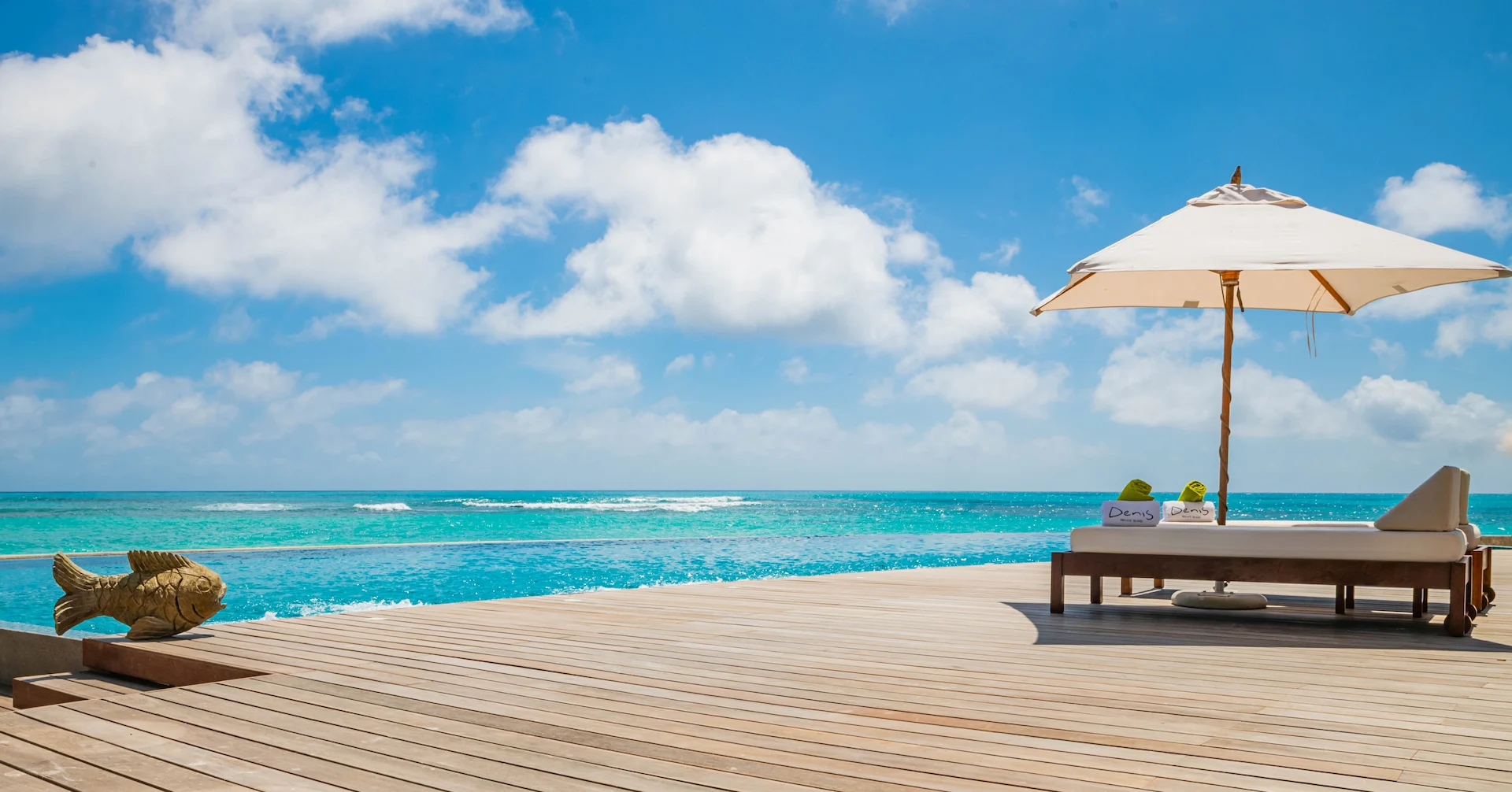 denis private island seychelles pool decking with sun loungers, tropical garden surroundings, and panoramic views of the turquoise ocean