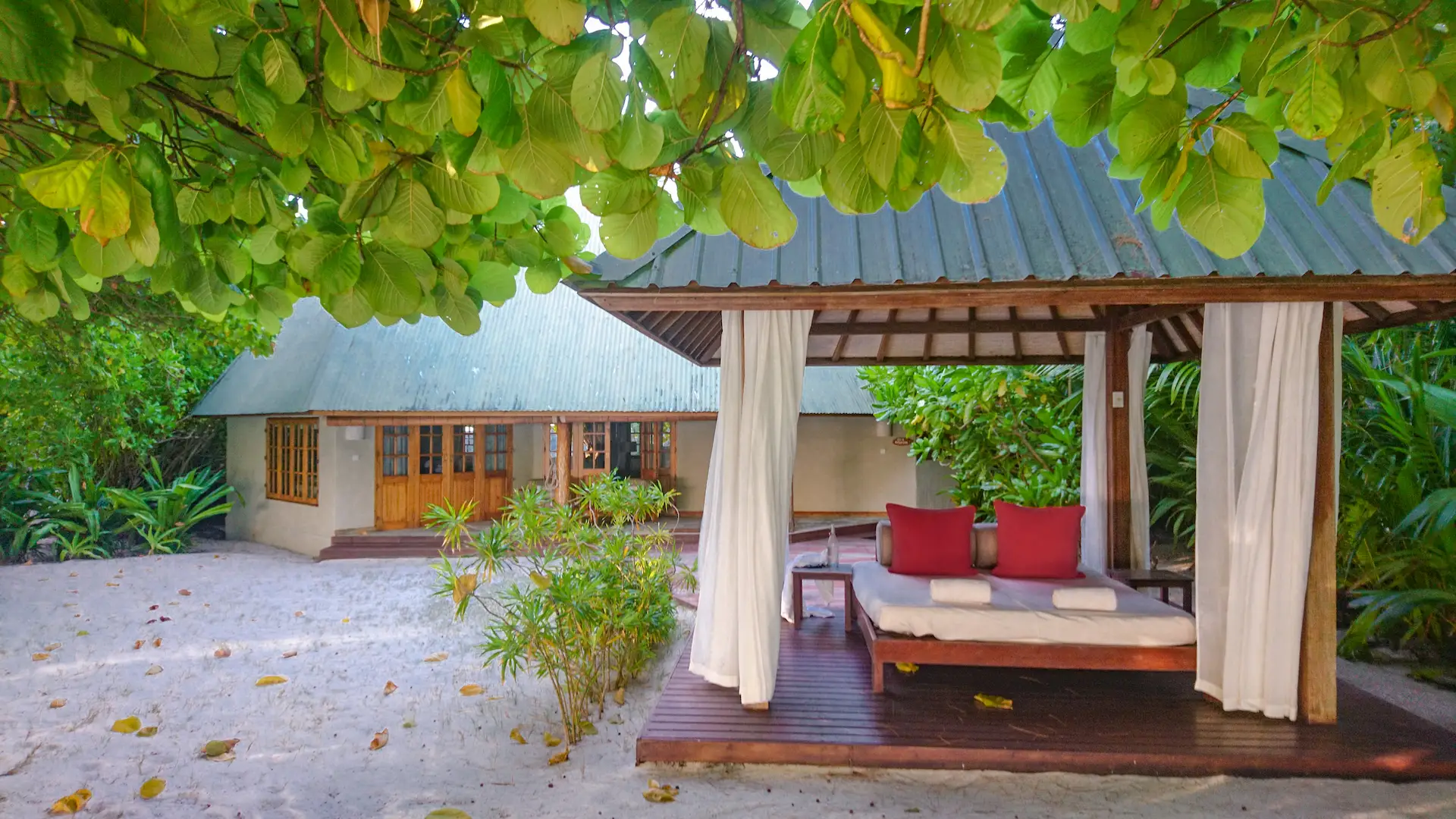 denis private island seychelles deluxe beach cottage exterior with spacious veranda, tropical garden surroundings, and direct access to pristine white sand beach