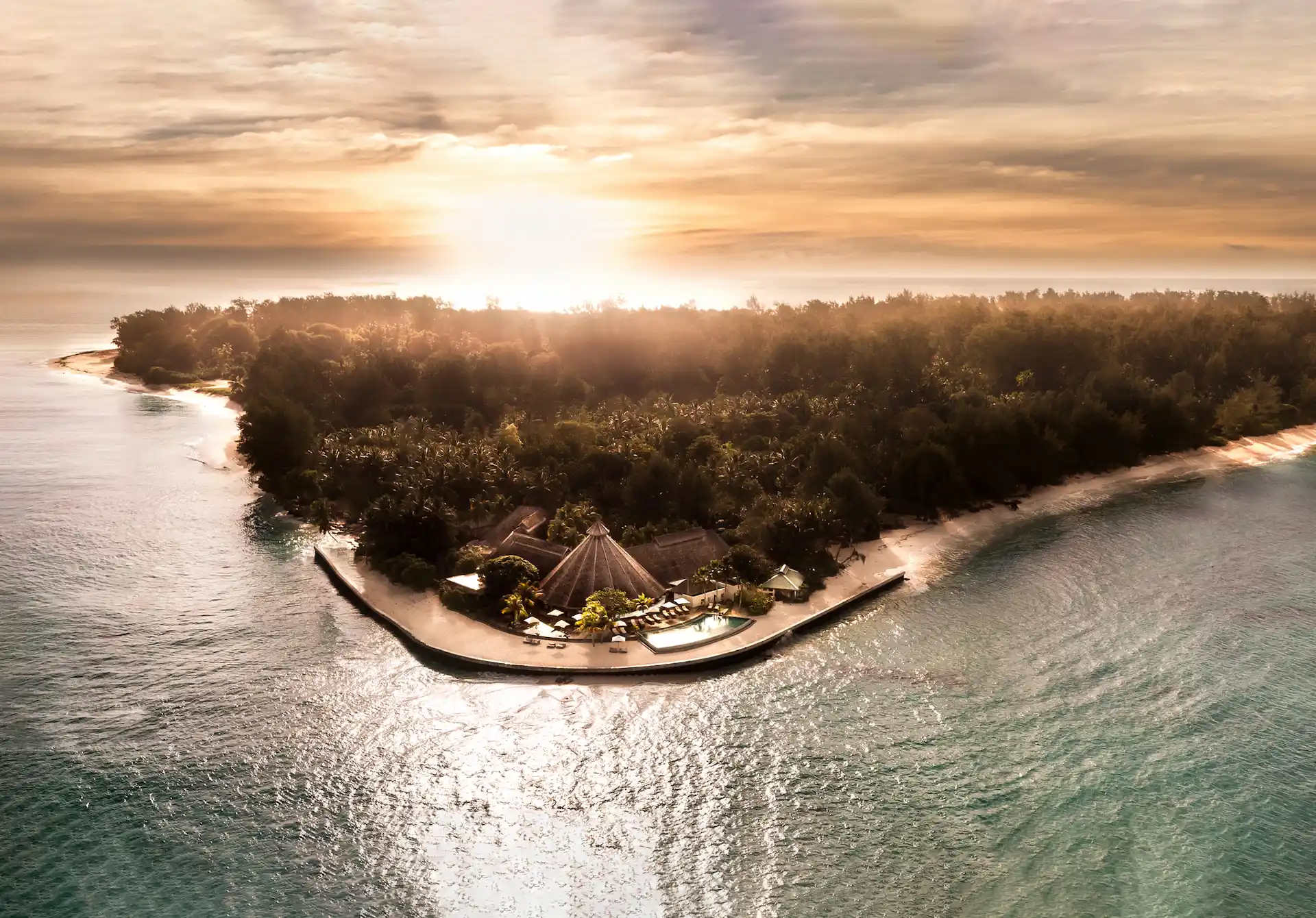 denis private island seychelles island sunset over turquoise waters with golden skies, white sand beaches, and tropical island backdrop