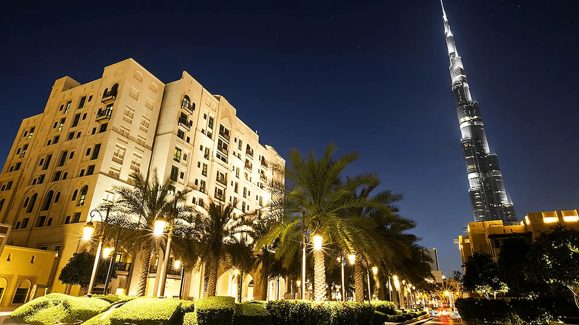 Burj Khalifa illuminated at night above the Dubai skyline with surrounding city lights and reflections