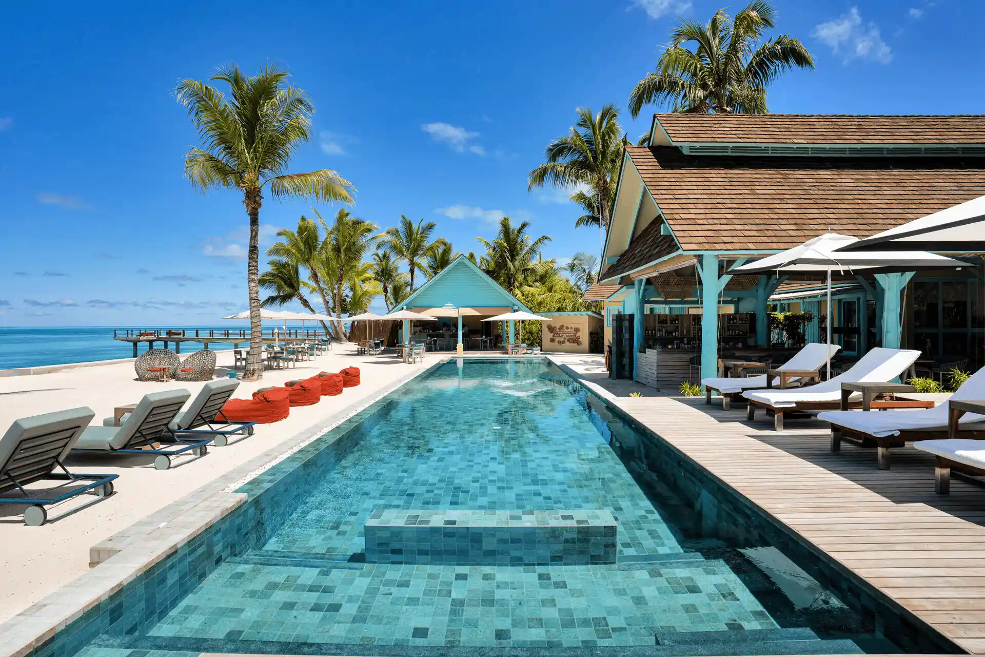 beach bar at four seasons resort desroches seychelles with seating area overlooking the ocean and sandy shoreline