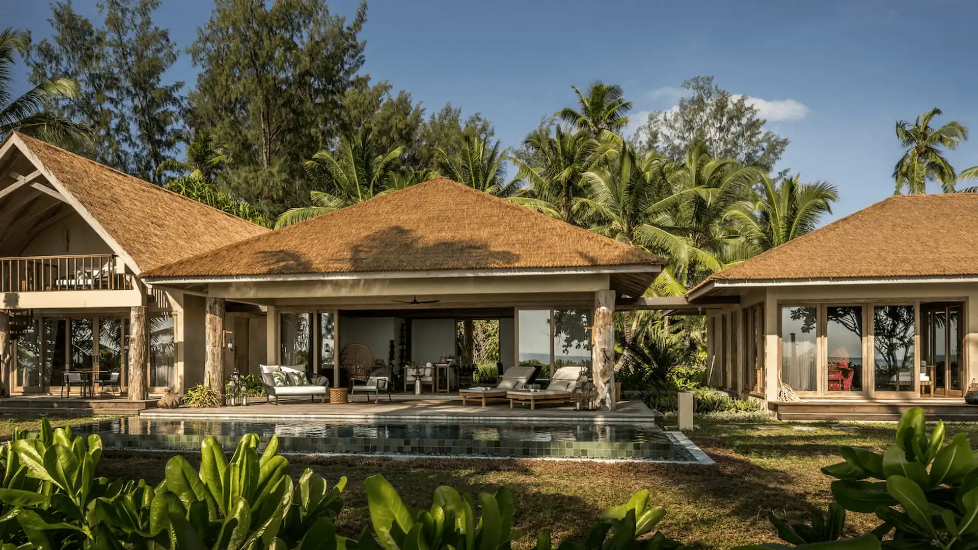 exterior of a two bedroom sunset beach suite at four seasons resort desroches seychelles surrounded by tropical greenery near the beach