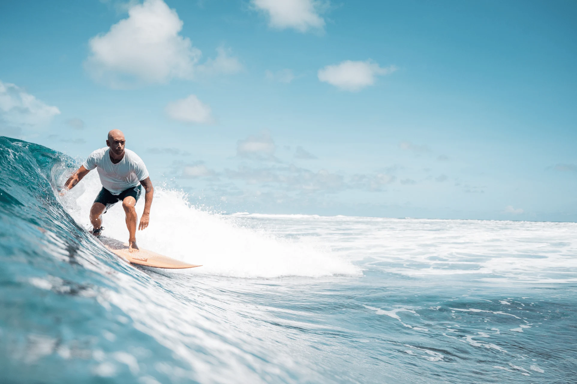 guest surfing in clear turquoise waters at four seasons resort desroches seychelles