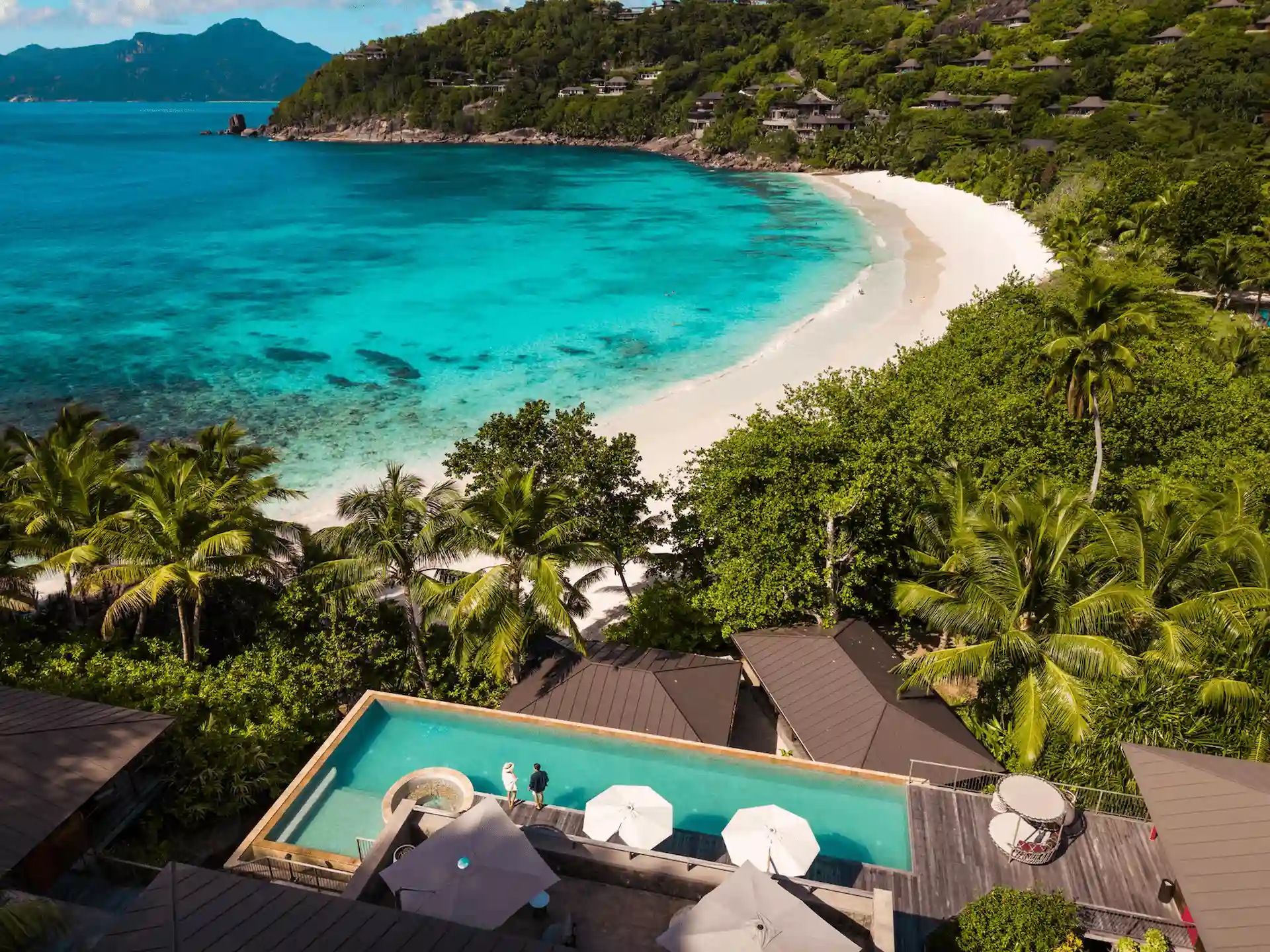 birds eye view of Four Seasons Resort Seychelles showing hillside villas, lush tropical forest, and the turquoise ocean coastline