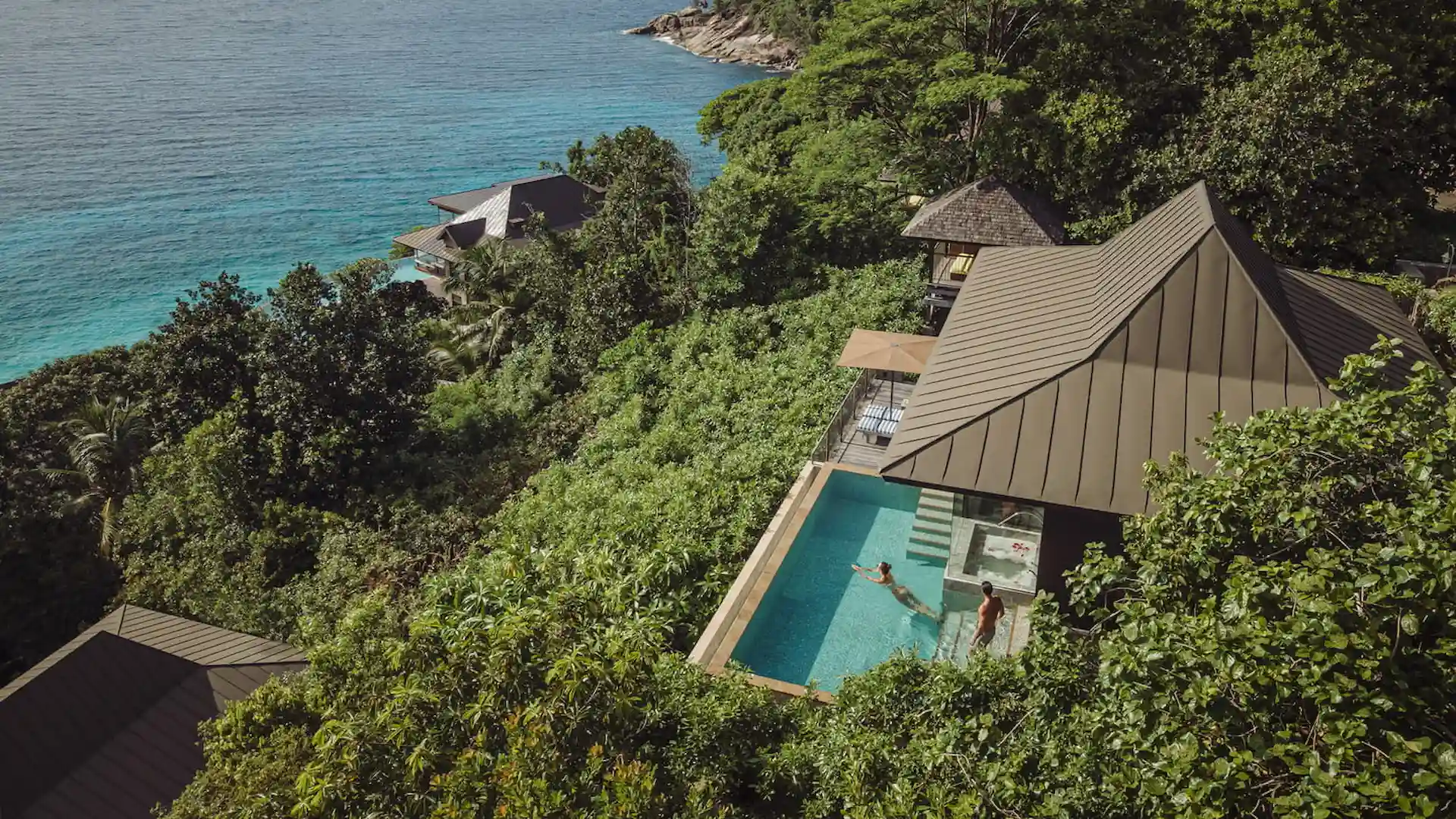 aerial pool view of a hillside ocean view villa at Four Seasons Resort Seychelles overlooking tropical forest and the ocean coastline