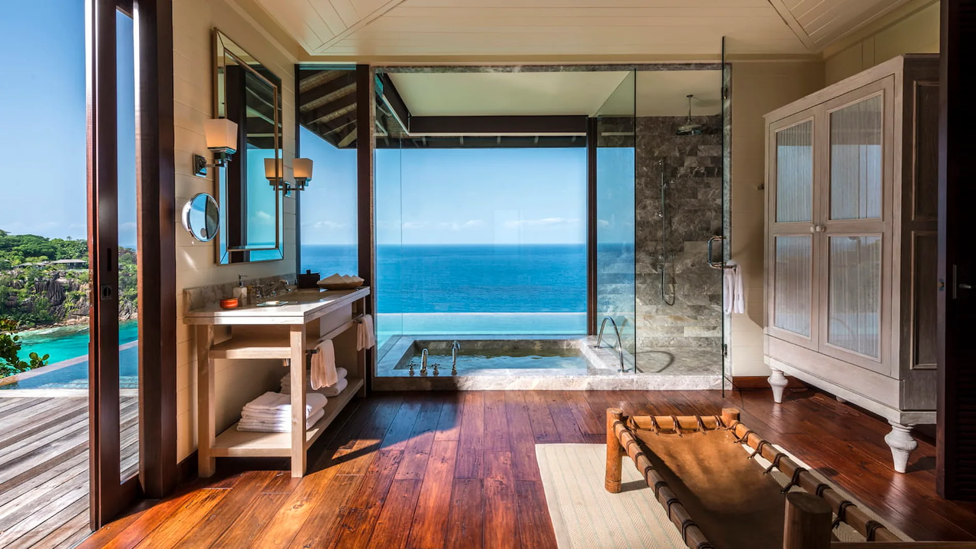 decking area of a hillside ocean view villa at Four Seasons Resort Seychelles with seating and views over tropical forest and the ocean