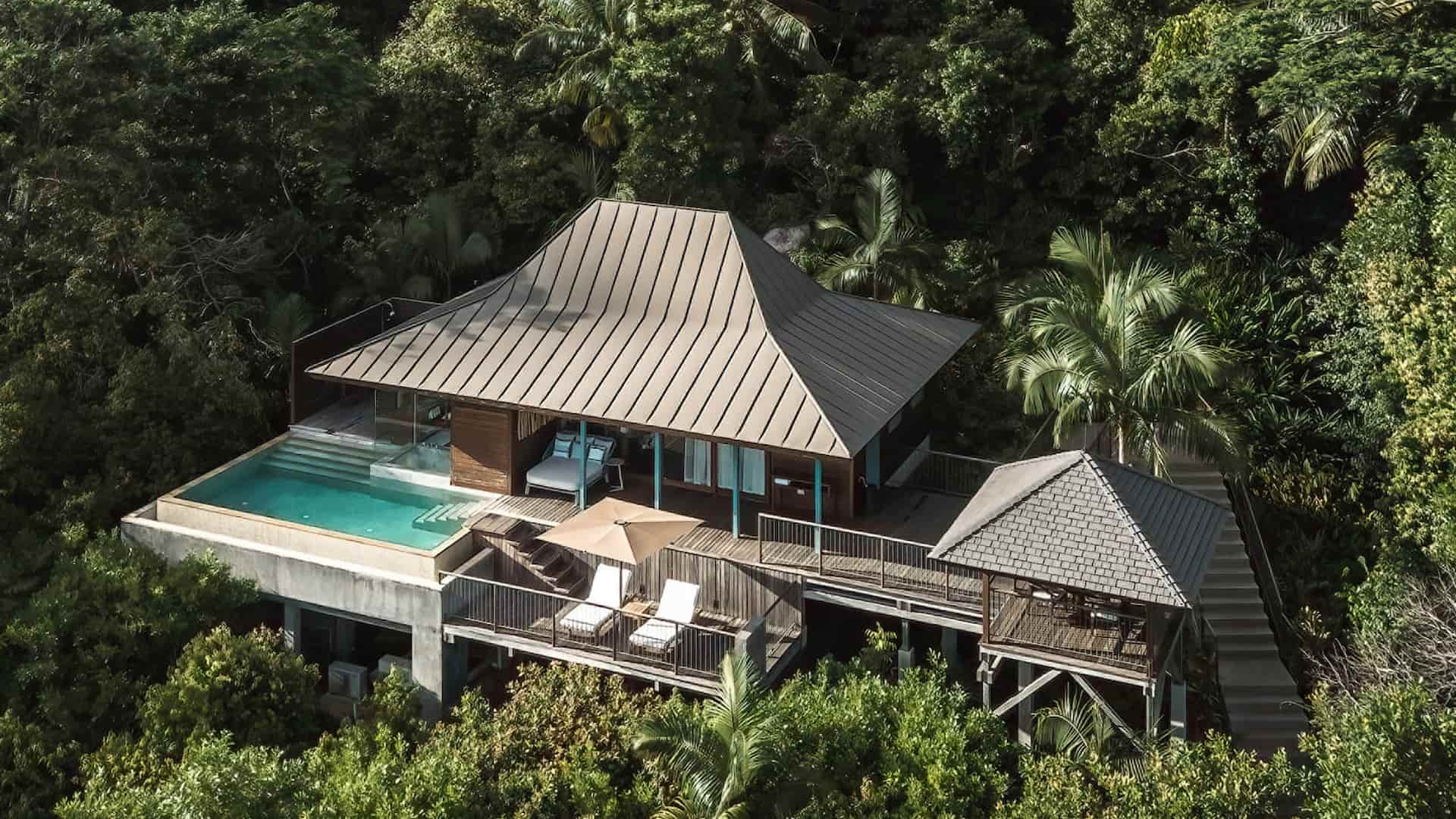 aerial view of ocean view villas at Four Seasons Resort Seychelles nestled in tropical hills overlooking the coastline and turquoise ocean