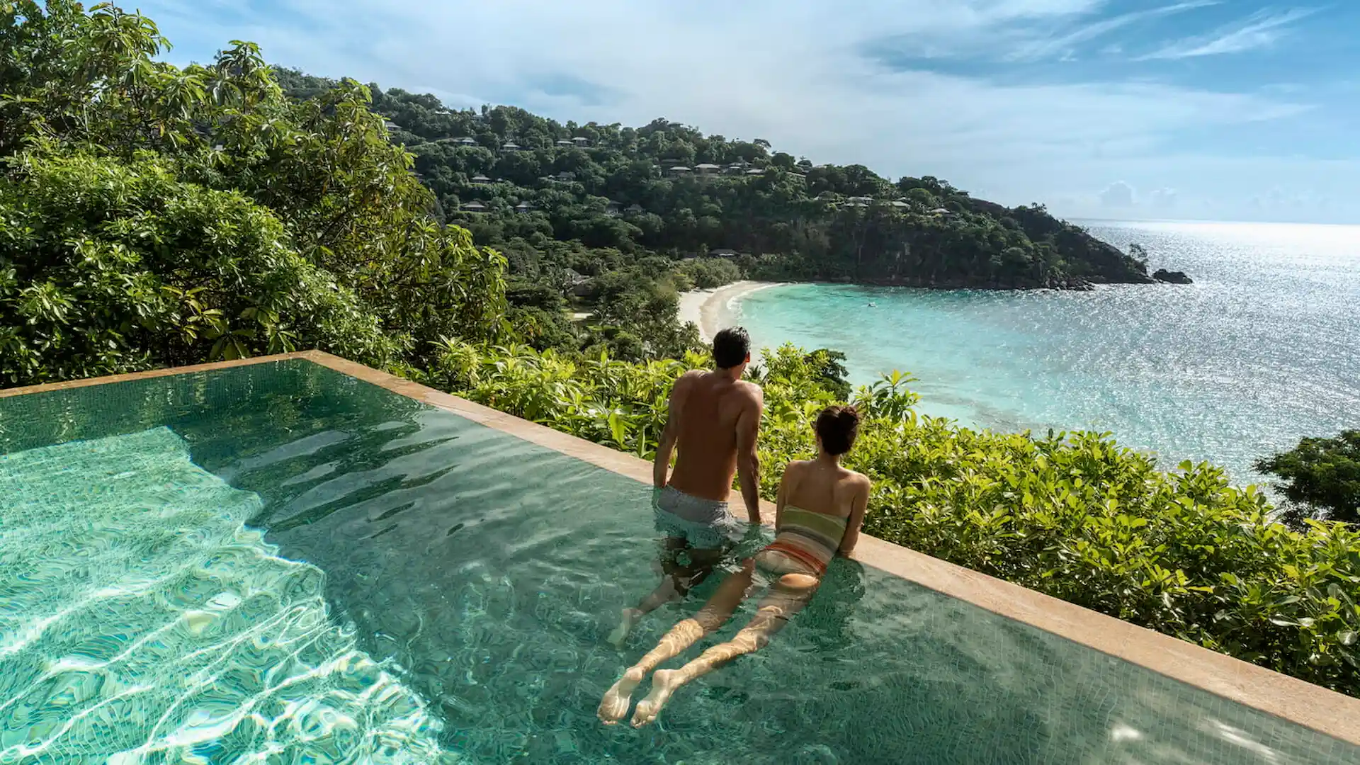 couple enjoying the private pool of a serenity villa at Four Seasons Resort Seychelles with tropical views and ocean backdrop