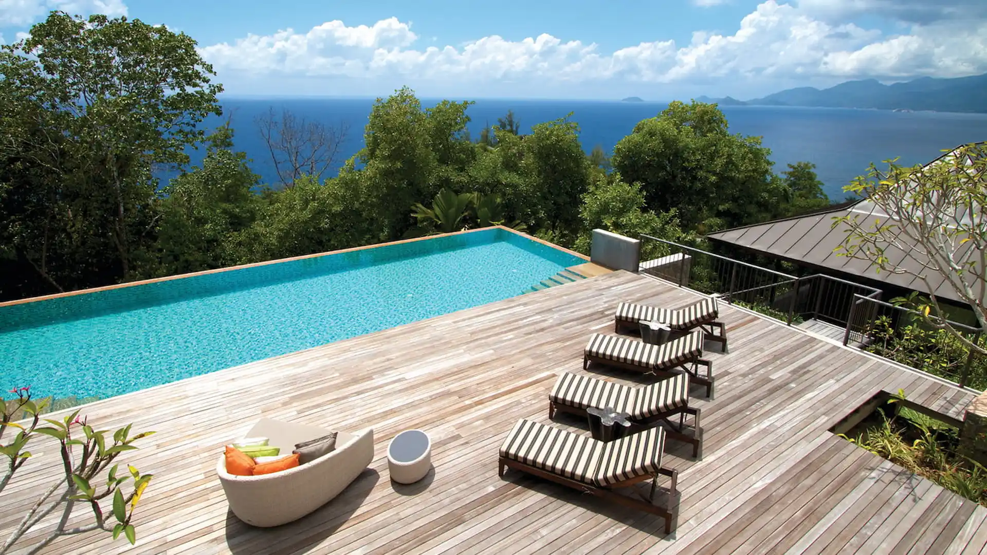 pool decking area of a three bedroom residence at Four Seasons Resort Seychelles with seating and tropical surroundings overlooking the ocean