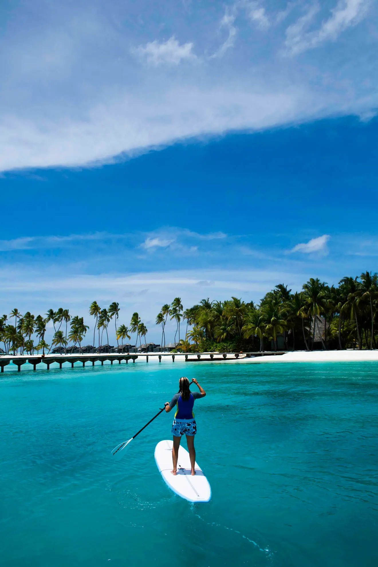 a peaceful paddle boarding experience at gili lankanfushi maldives gliding across calm turquoise lagoon waters