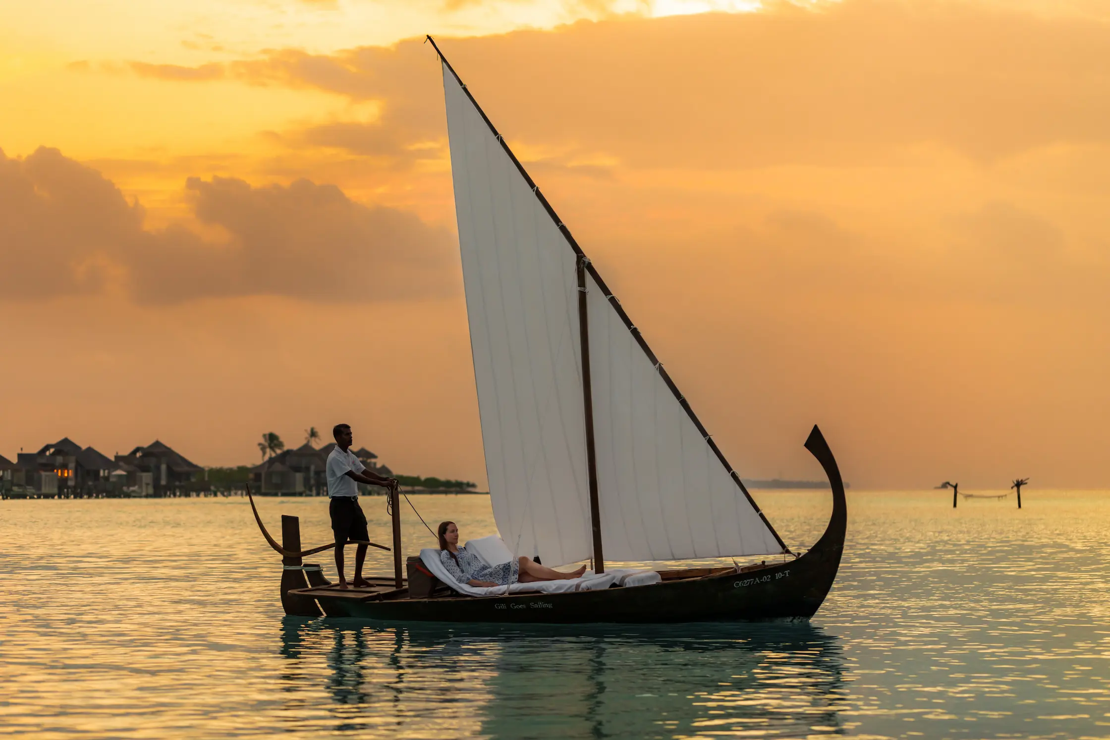 a tranquil sunset sailing experience at gili lankanfushi maldives gliding across soft golden lagoon waters