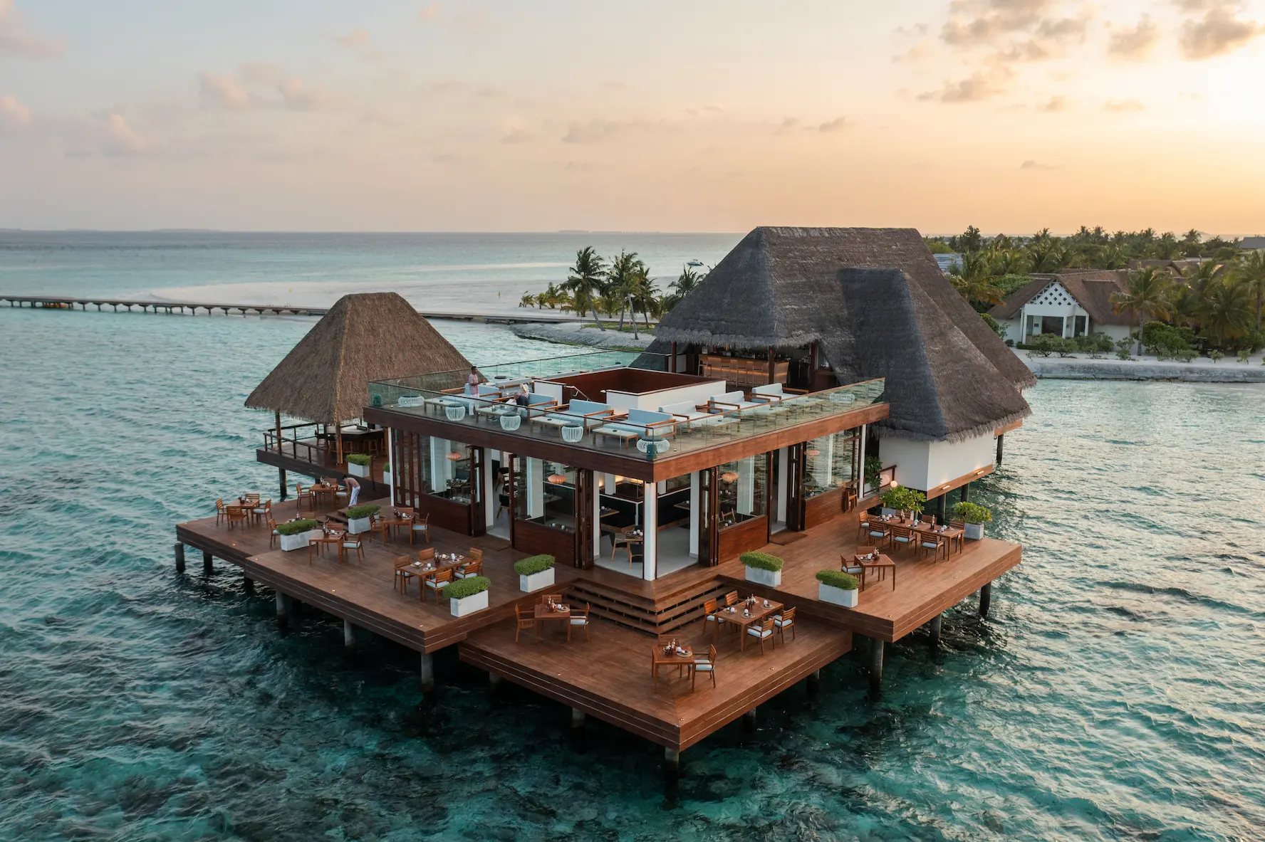 heritance aarah maldives aerial view ambula at sunset showcasing a serene island dining setting with warm golden light and tranquil ocean ambience