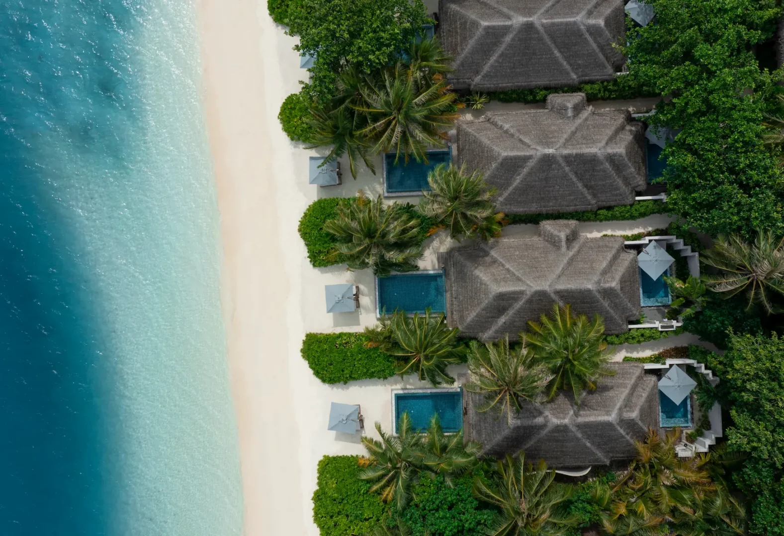heritance aarah maldives deluxe beach bungalow aerial showcasing a serene beachfront layout surrounded by turquoise lagoon waters and lush tropical greenery