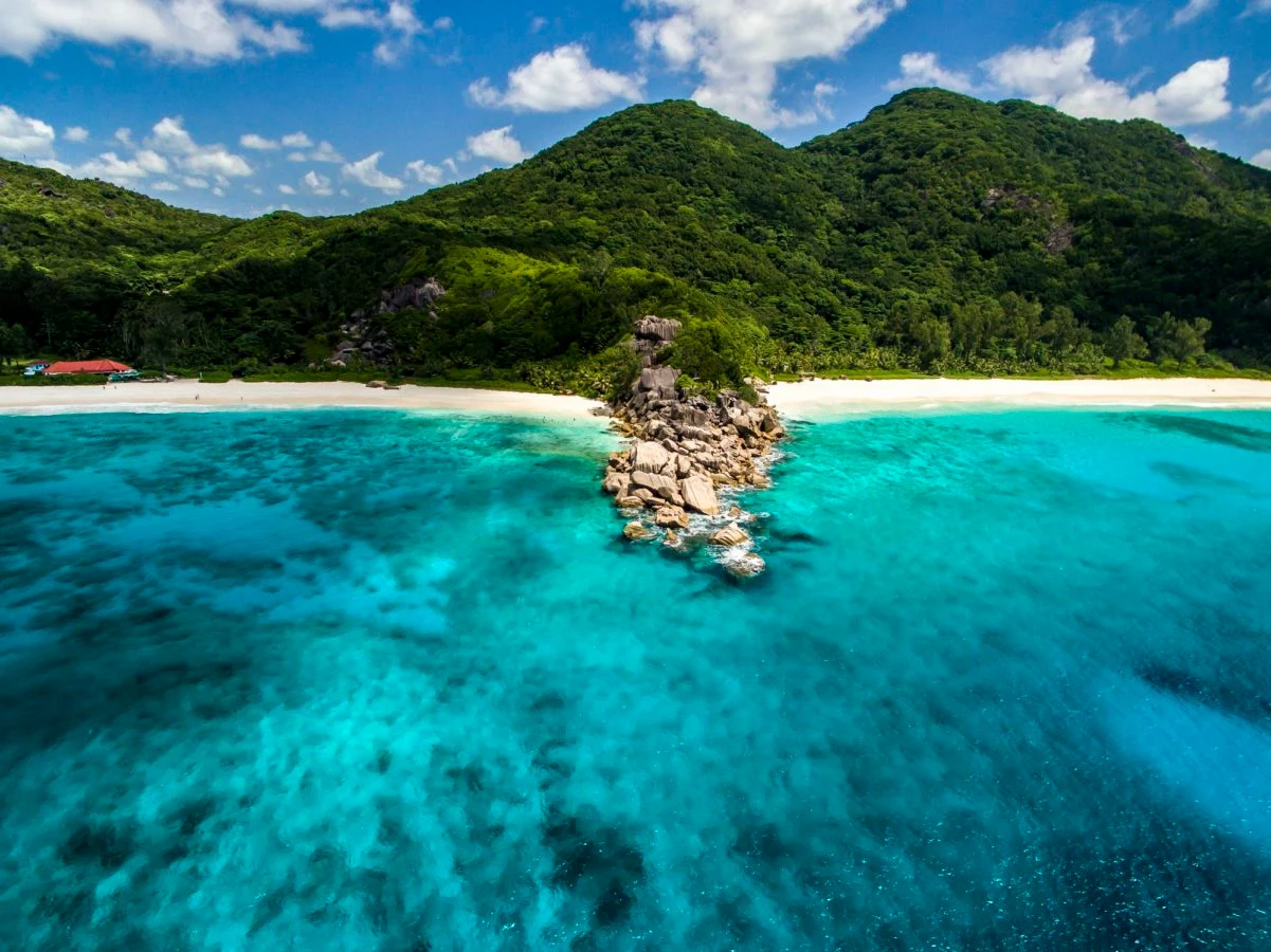 aerial view of the island surrounding Le Domaine de L’Orangeraie Resort & Spa showing lush tropical vegetation, coastline, and turquoise ocean
