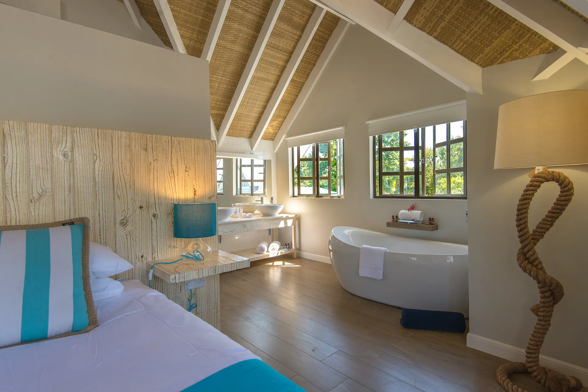 bed in a king deluxe seafront room at Le Nautique with a large bed and views of the ocean and tropical surroundings
