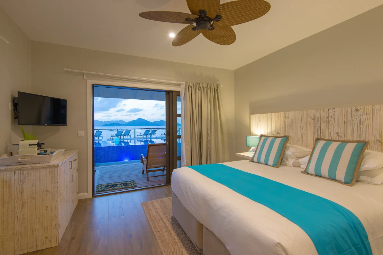 seafront room at Le Nautique with a bed facing windows that overlook the ocean and tropical coastline