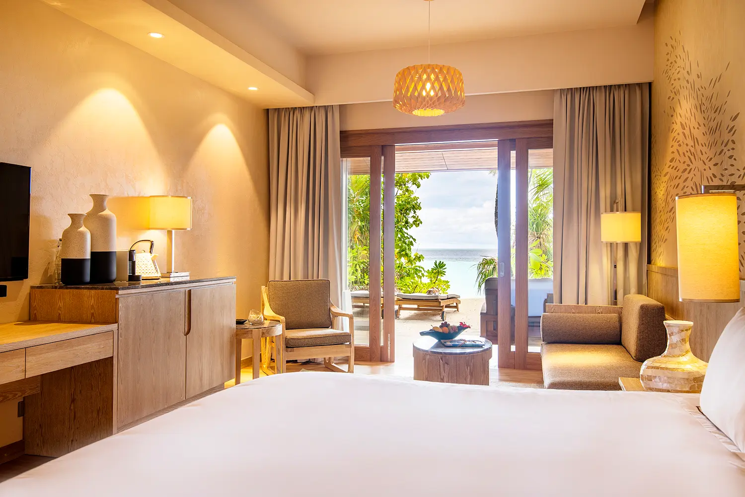 lily beach maldives beach suite bed with view overlooking the shoreline with soft natural light and serene tropical ocean ambience