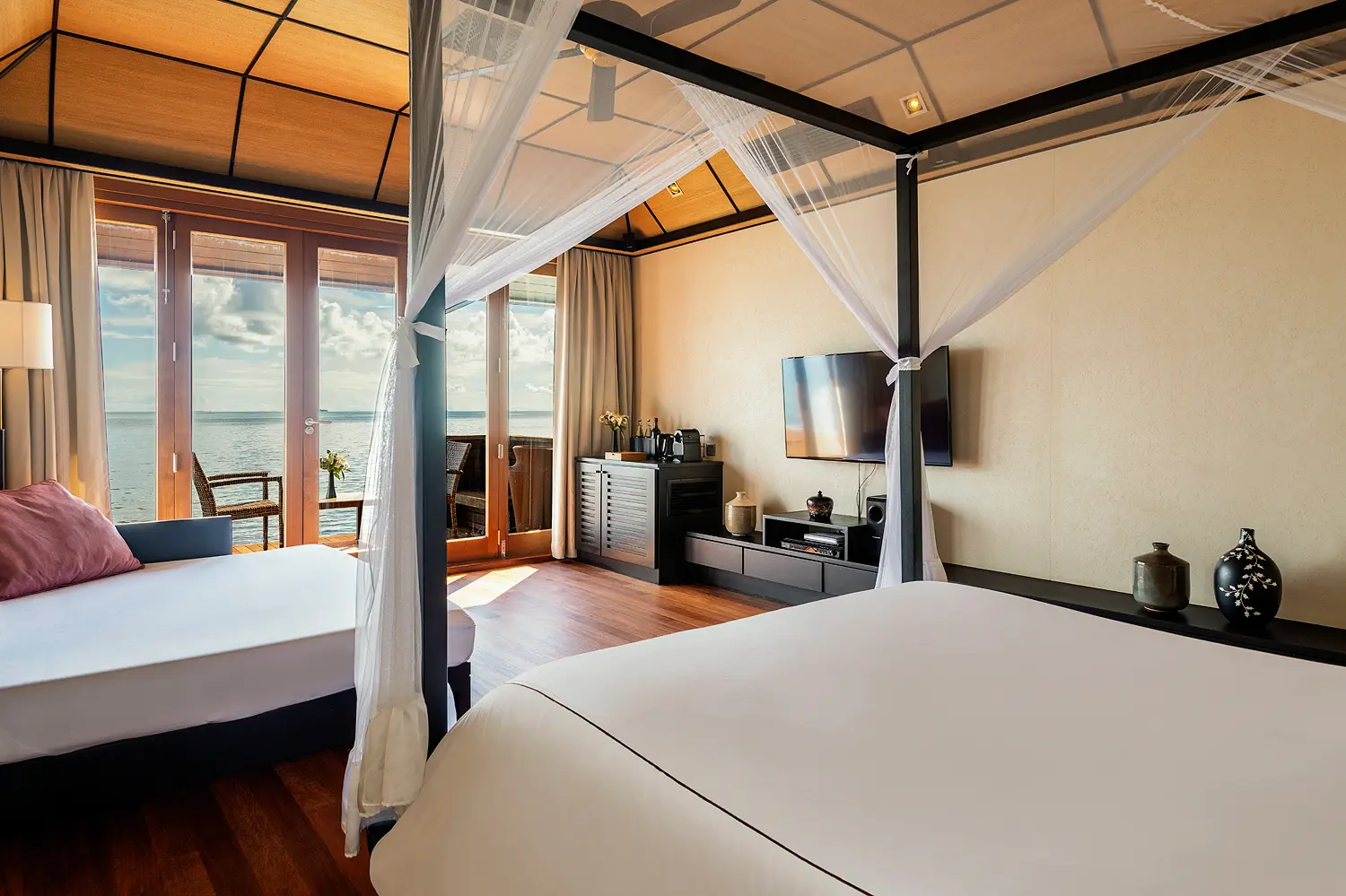 lily beach maldives deluxe water villa bed with a serene lagoon backdrop featuring soft natural light and elegant tropical luxury