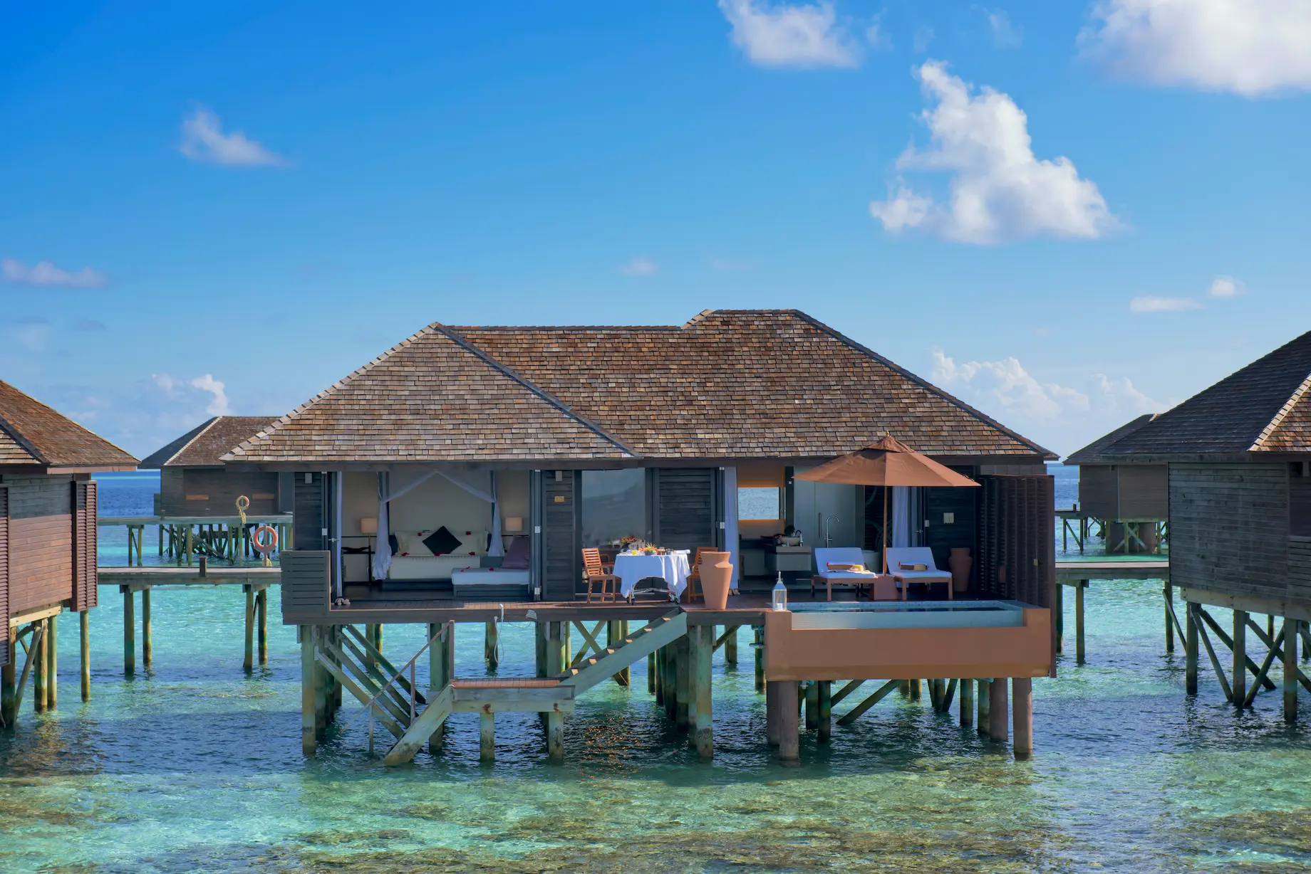lily beach maldives deluxe water villa exterior set above the turquoise lagoon with elegant wooden design and serene tropical ocean views