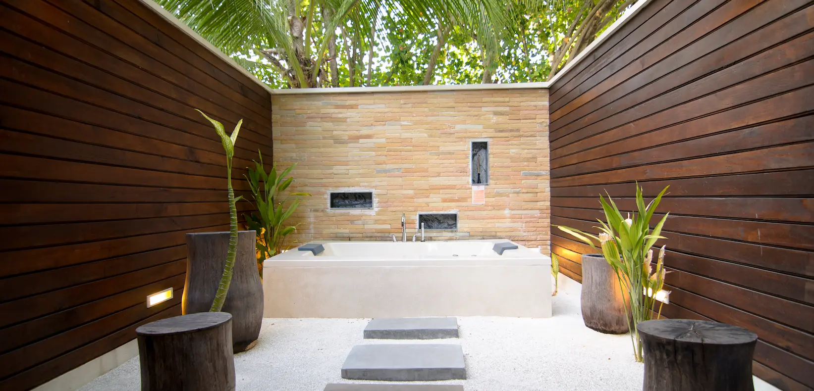 lily beach maldives lagoon villa outdoor bathtub surrounded by lush tropical greenery offering a serene open air bathing experience with peaceful lagoon views