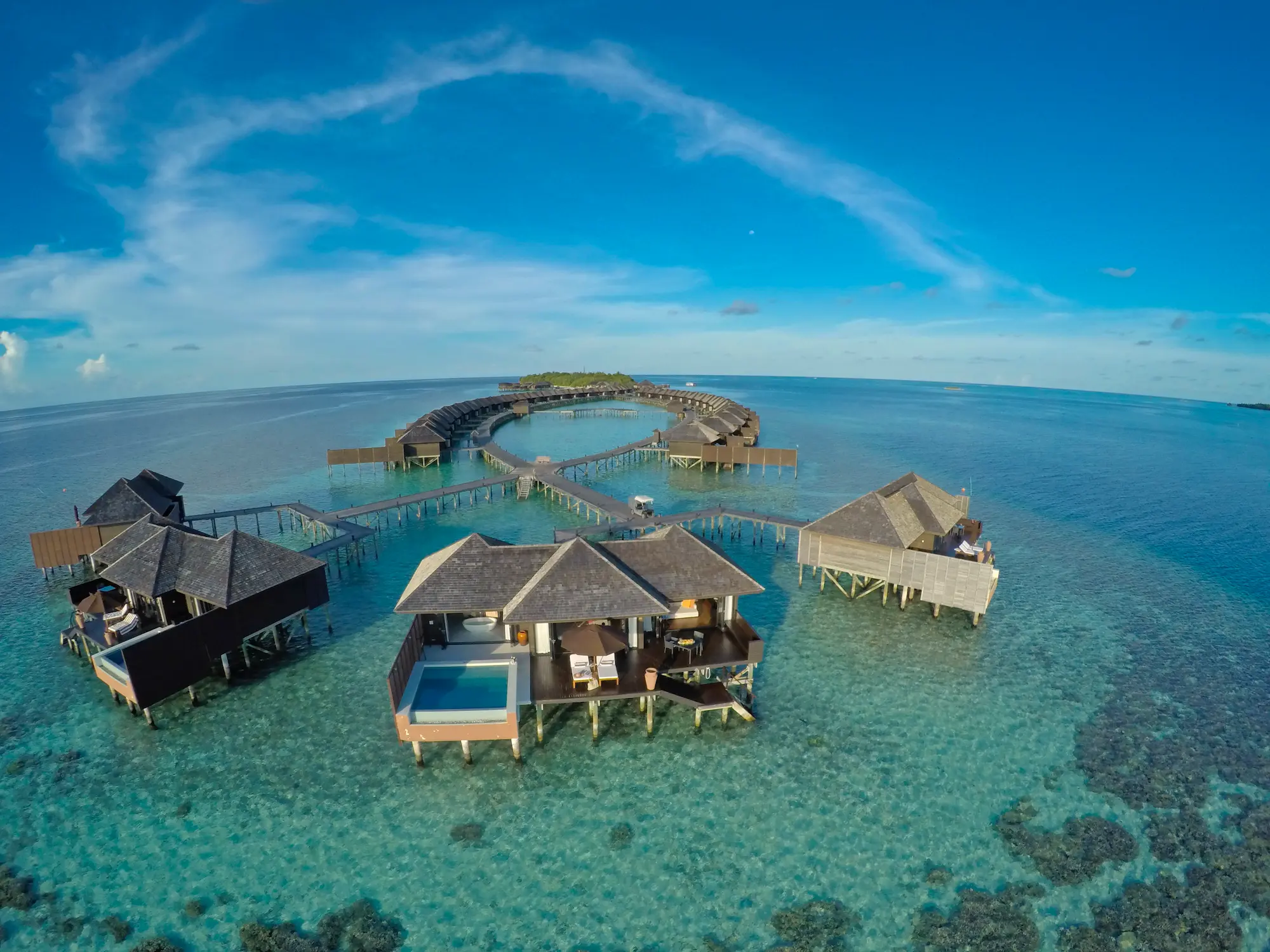 lily beach maldives sunset water suites aerial view showcasing the villas set above the turquoise lagoon with serene tropical surroundings and soft sunset tones