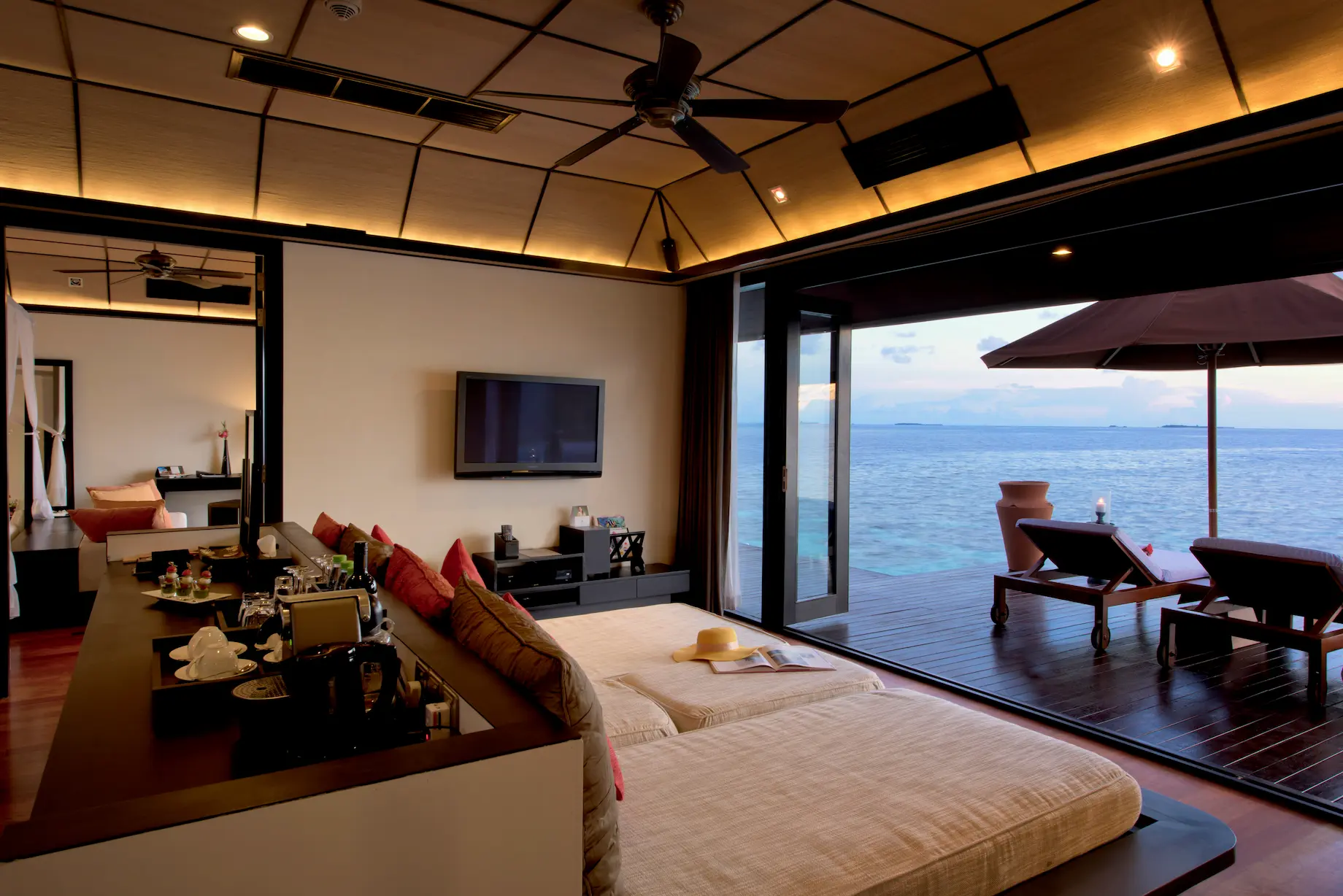 lily beach maldives sunset water suites day bed overlooking the tranquil lagoon with soft natural light and a serene tropical ambience