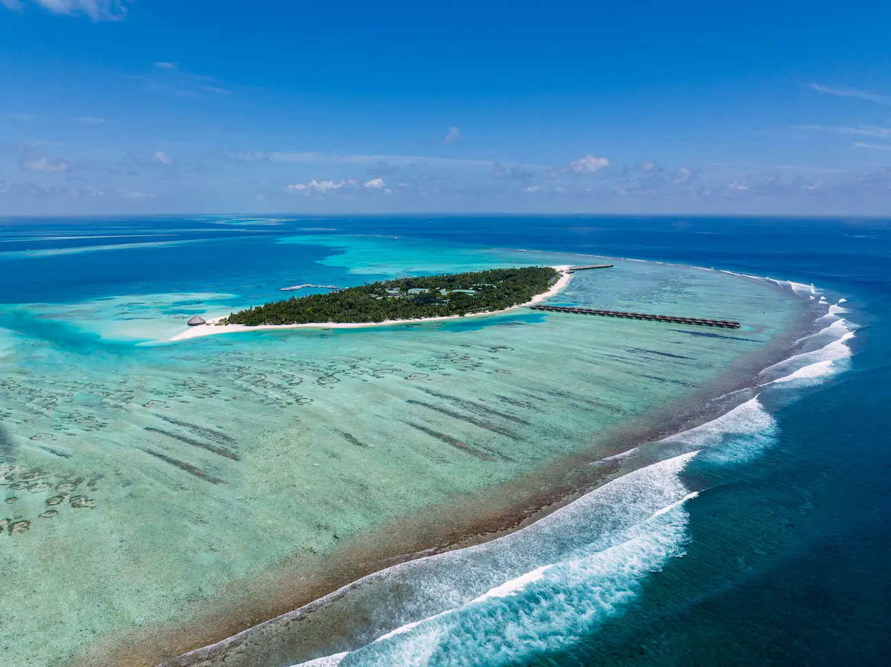 meeru maldives aerial island view with turquoise lagoon white sandy shoreline and lush tropical greenery creating a serene relaxed luxury atmosphere