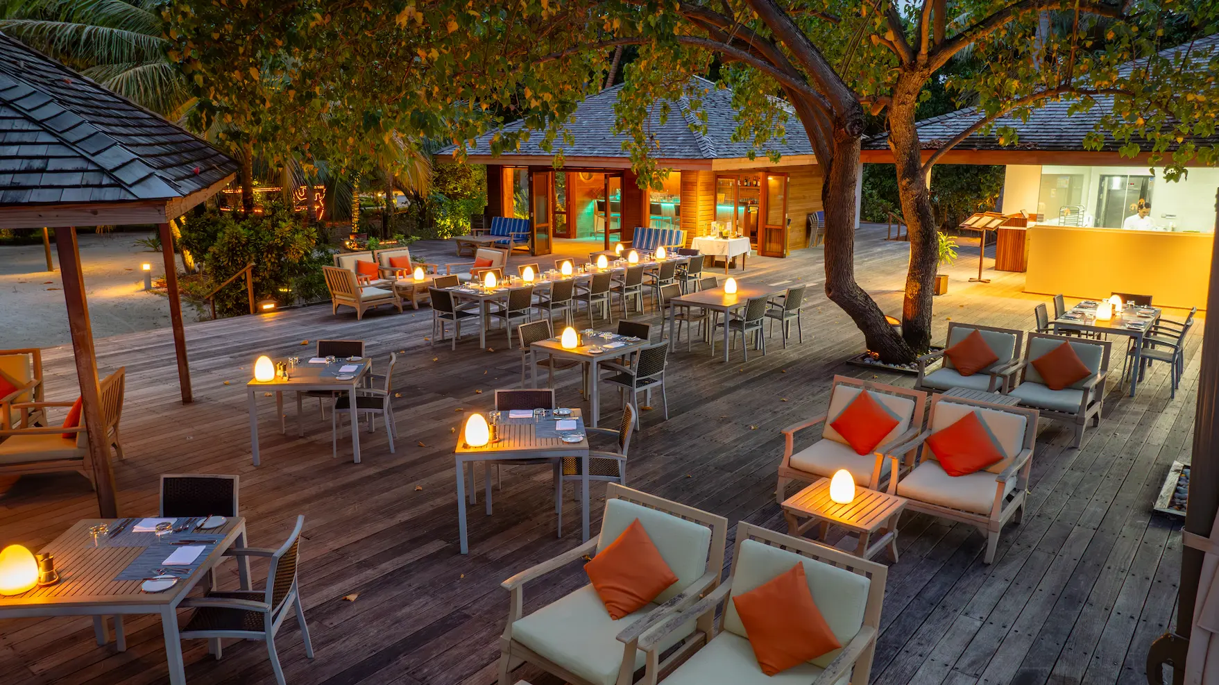meeru maldives amare outdoor seating with warm natural light elegant wooden furnishings and a serene beachfront atmosphere reflecting the resort’s relaxed luxury style