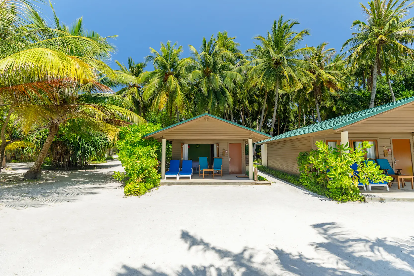meeru maldives beach villa exterior surrounded by tropical greenery with warm natural light highlighting the clean architecture and serene luxury resort atmosphere