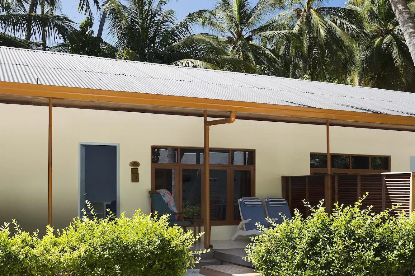 meeru maldives garden room exterior surrounded by tropical greenery with warm natural light highlighting the clean architecture and serene resort ambiance