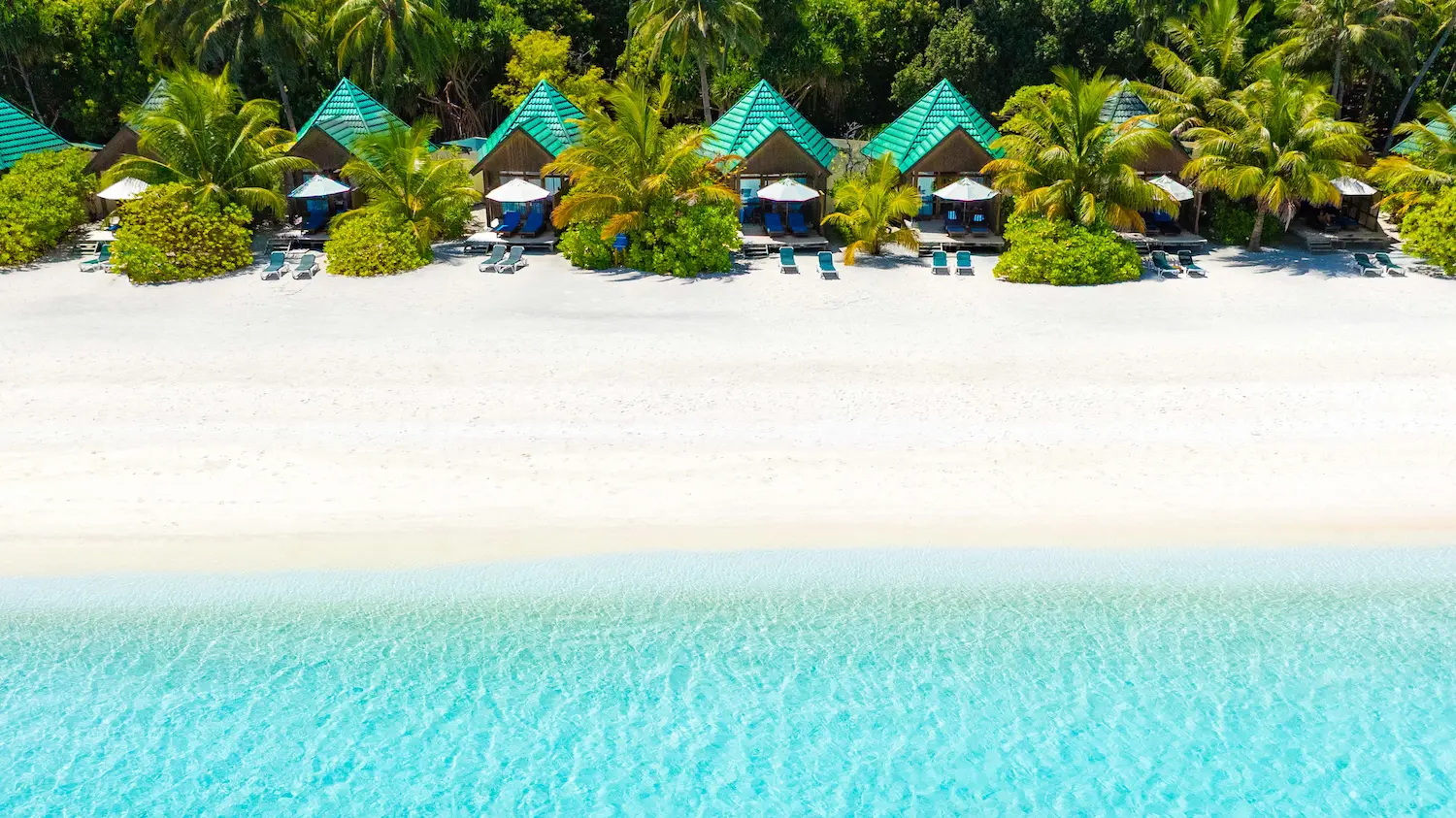 meeru maldives waterfront villa aerial view showcasing turquoise lagoon lush tropical greenery and a serene beachfront setting that reflects the resort’s relaxed luxury atmosphere