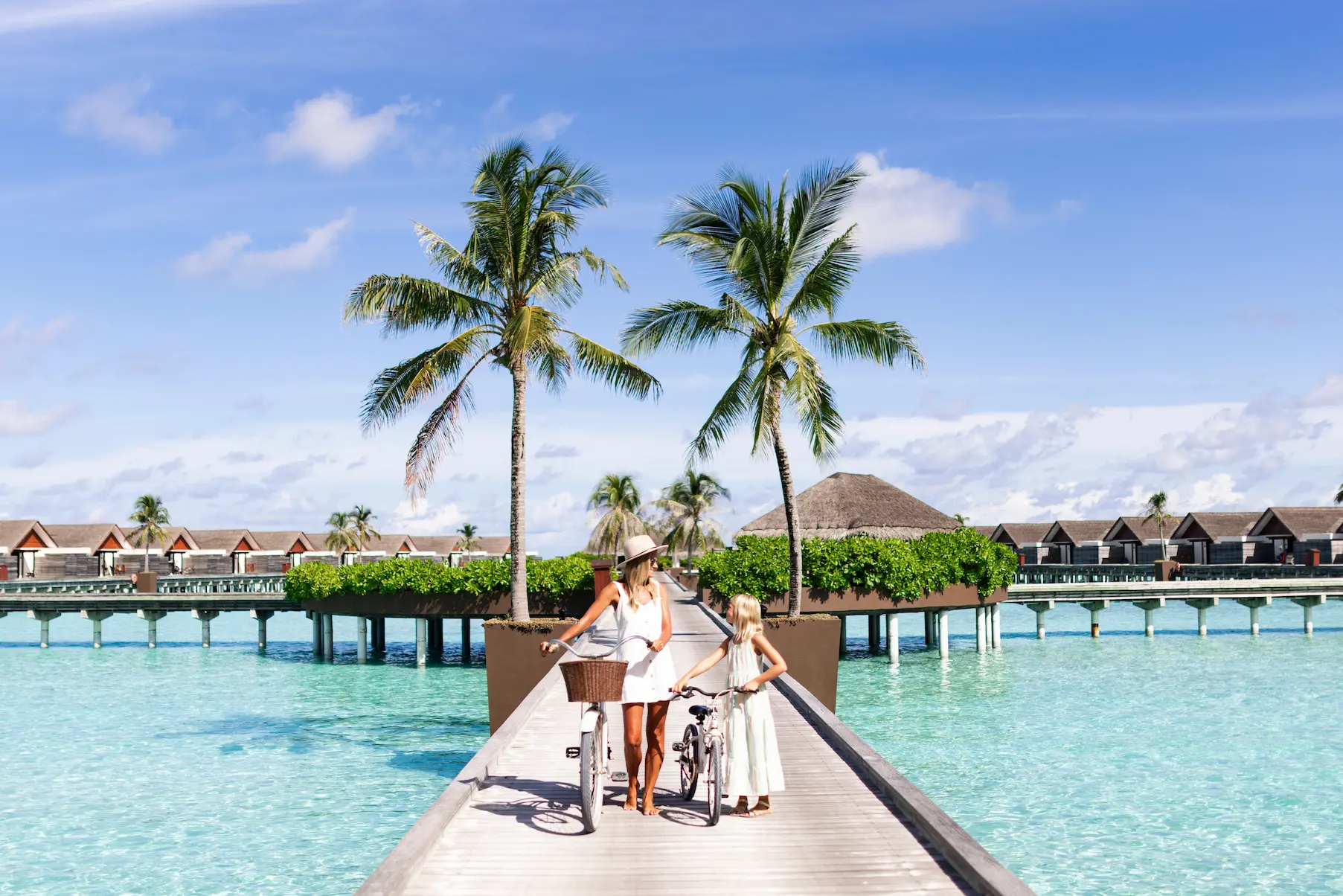 niyama private islands maldives mom and daughter walking with bicycle on the over water jetty enjoying serene ocean views and relaxed island atmosphere