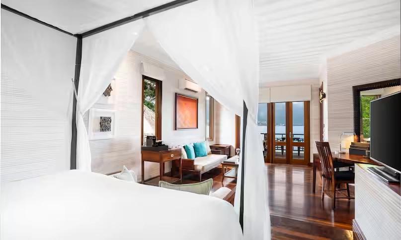 king-sized bed in northolme king sunset villa with tropical decor, soft linens, and ocean view through large windows