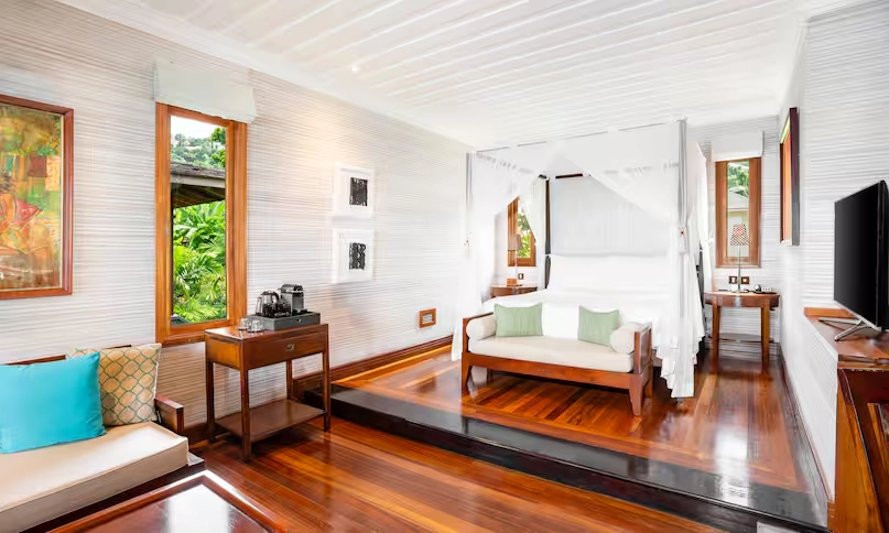 king-sized bed in northolme king ocean view villa with tropical decor, soft linens, and large windows overlooking turquoise ocean