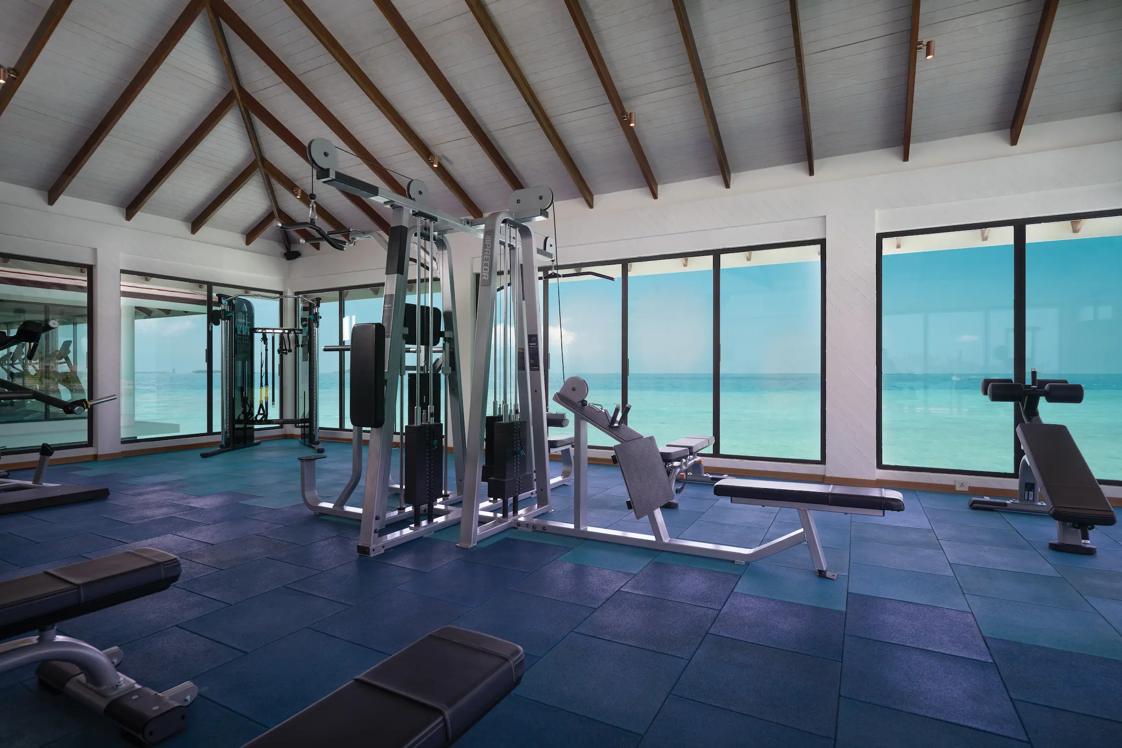 oblu select lobigili maldives overwater gym interior modern fitness space with panoramic ocean views natural light and refined island wellness design