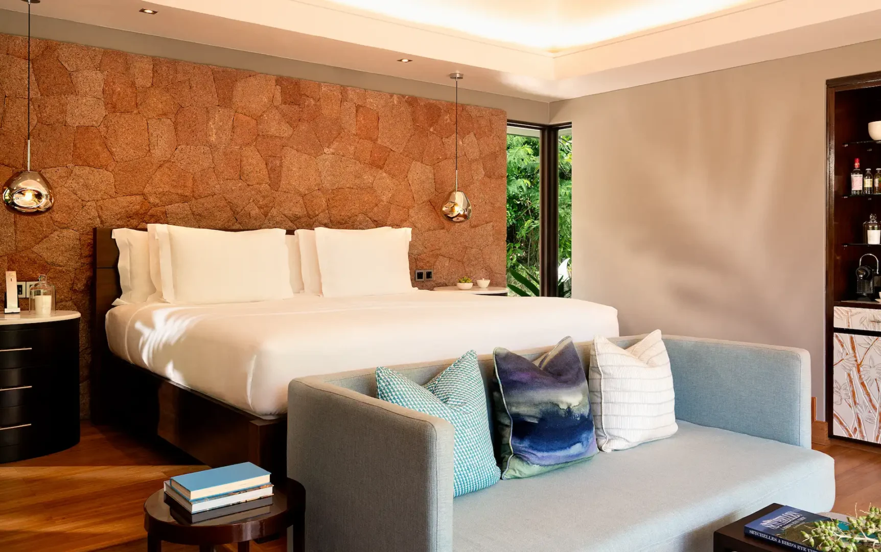 ocean view pool villa in seychelles with bed, sofa seating, and turquoise sea visible from the room