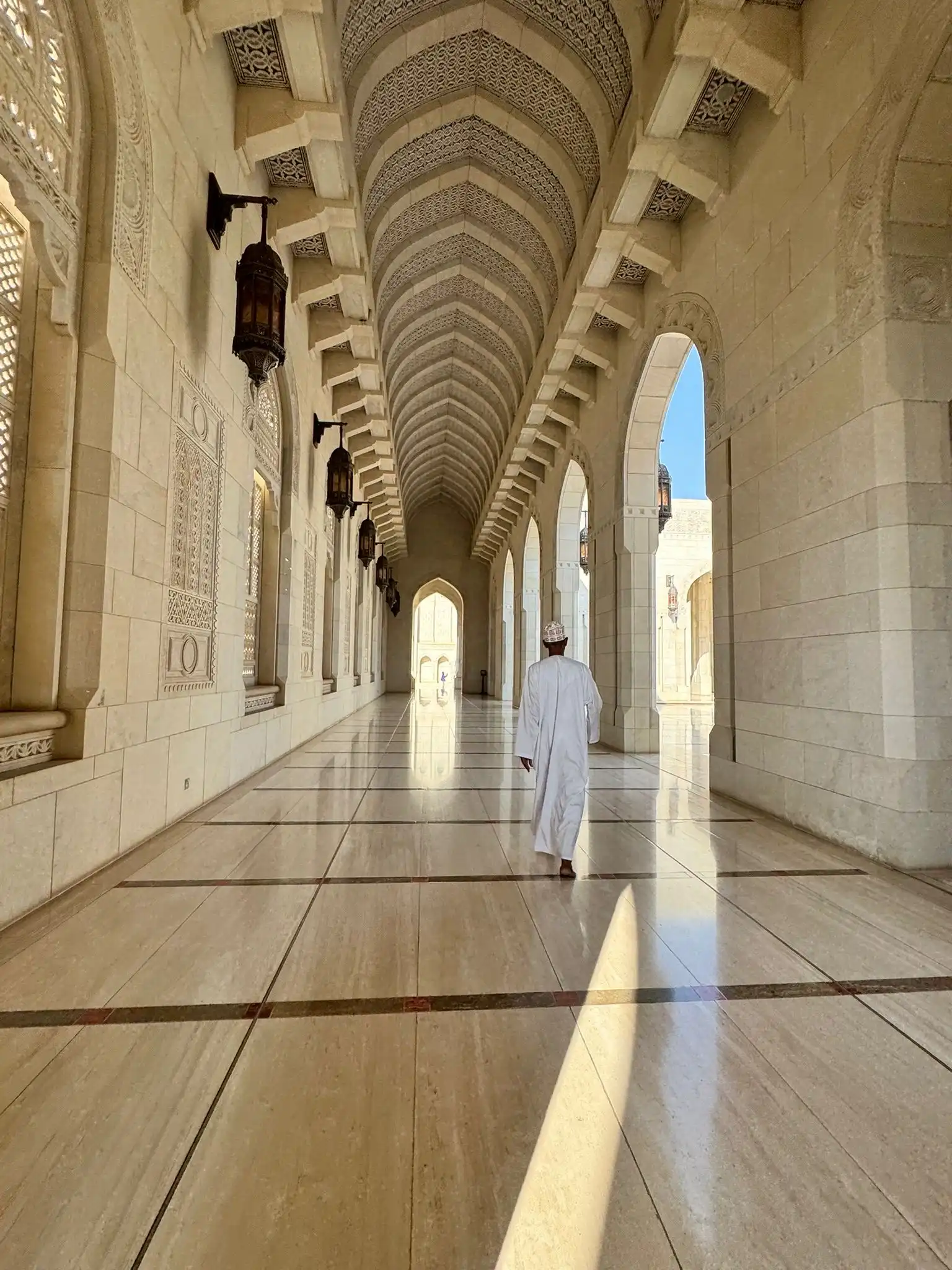 oman mosque with traditional islamic architecture, large central dome, minarets, and intricate geometric patterns surrounded by open courtyard and clear skies