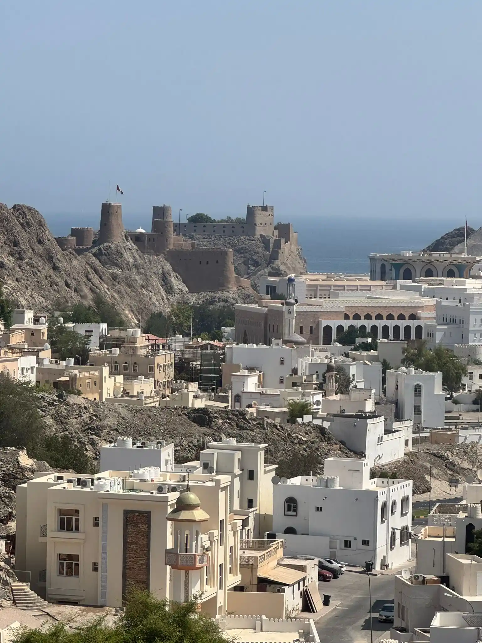 oman muscat cityscape with the grand mosque, coastal mountains, and sparkling turquoise waters along the harbor