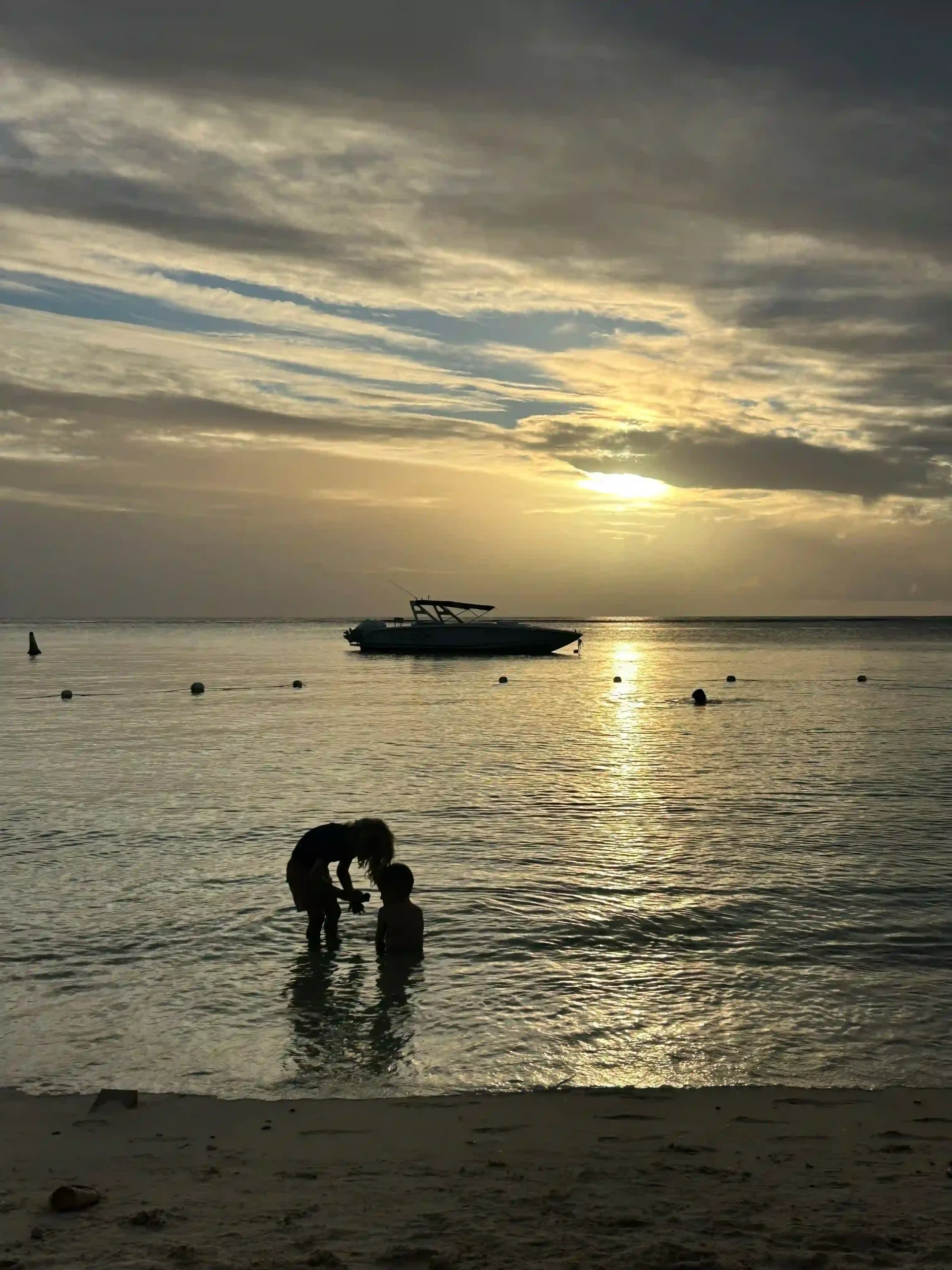 paradis mauritius sunset with children playing on the beach, golden skies reflecting on turquoise waters, and swaying palm trees along the shoreline