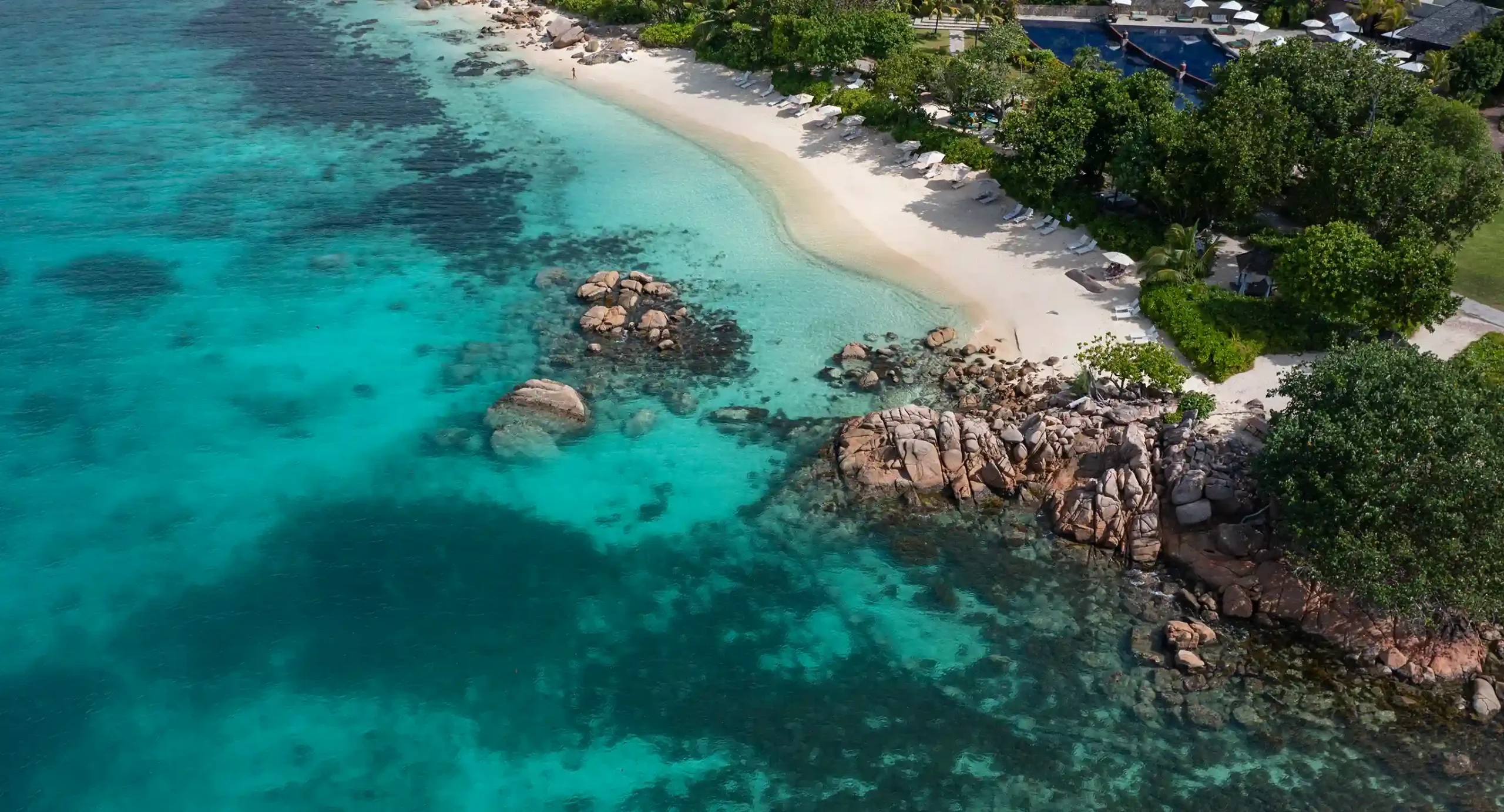 aerial view of raffles seychelles beach with white sand, turquoise water, and surrounding tropical greenery