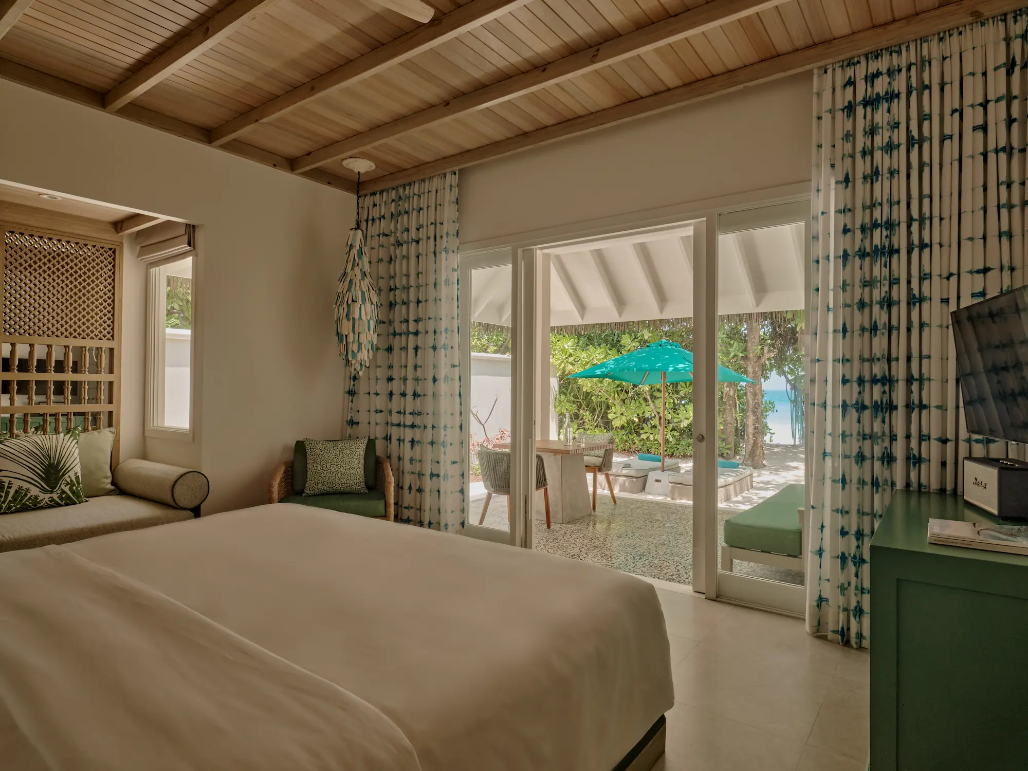 seaside finolhu beach villa bedroom featuring elegant coastal design warm natural textures and serene maldives island ambience