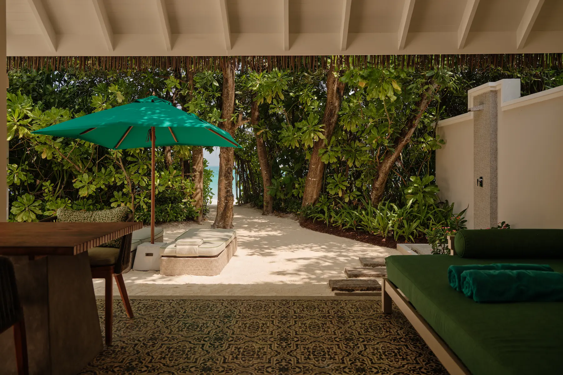 seaside finolhu beach villa terrace with private outdoor lounging space lush tropical greenery and serene maldives island ambience