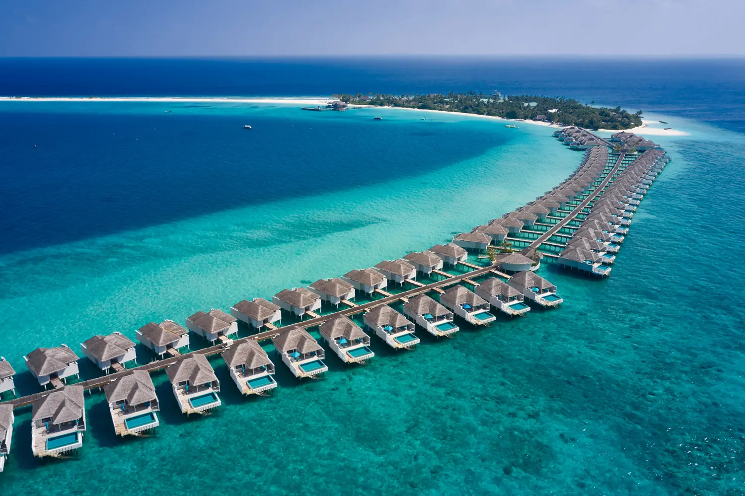 seaside finolhu maldives drone shot of water villas elevated view showcasing the overwater villas set above clear turquoise lagoon waters
